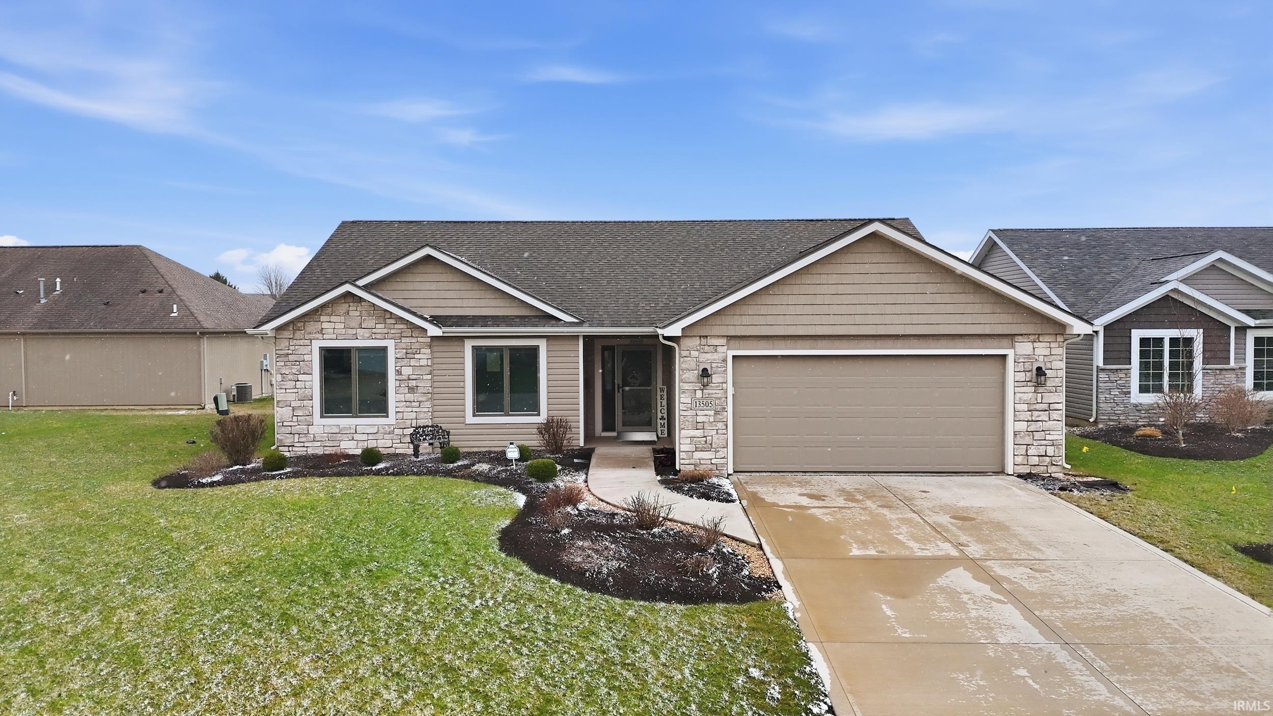 Craftsman-style house featuring stone siding, a front lawn, concrete driveway, and a garage