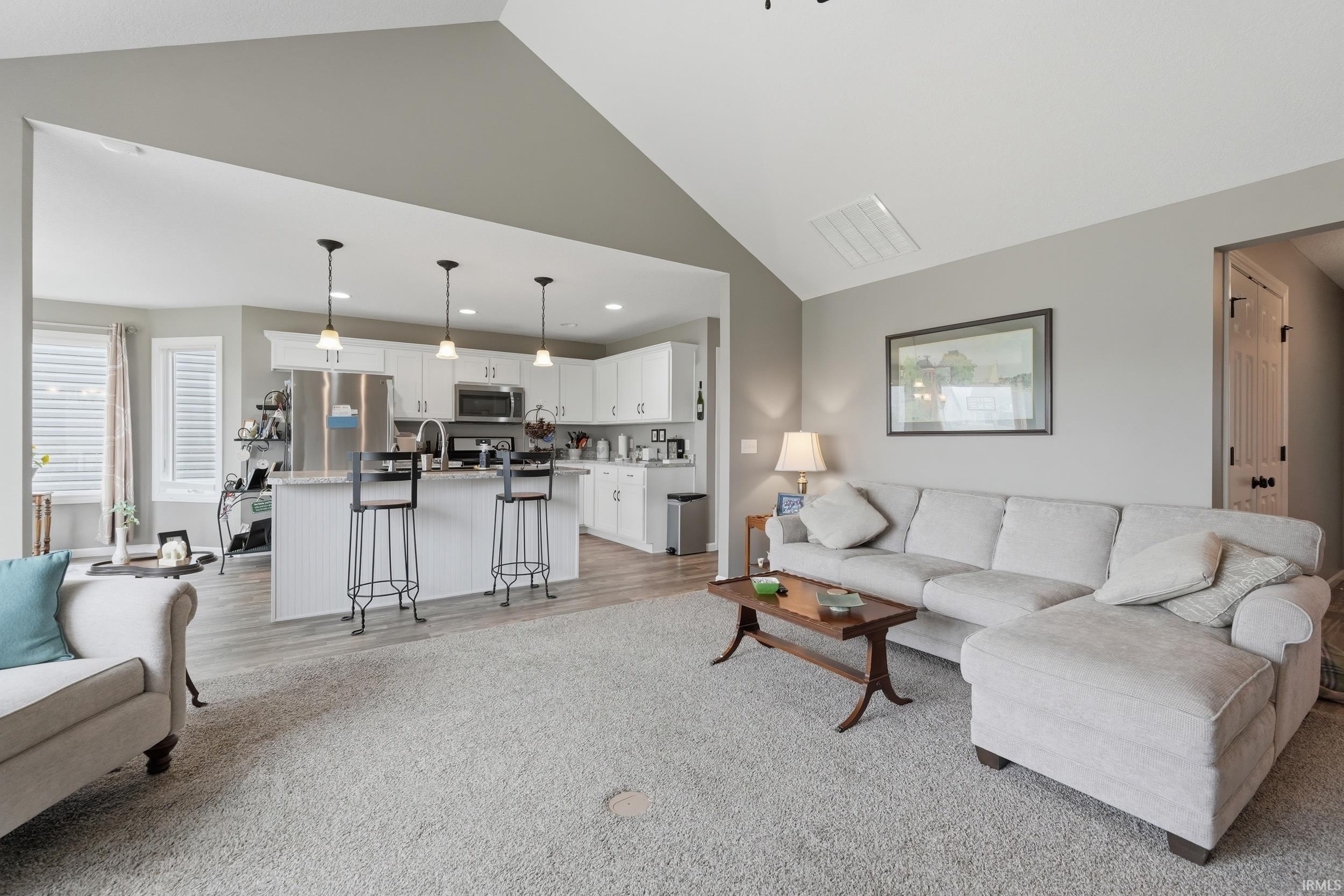 Living room with lofted ceiling, light wood-type flooring, and recessed lighting