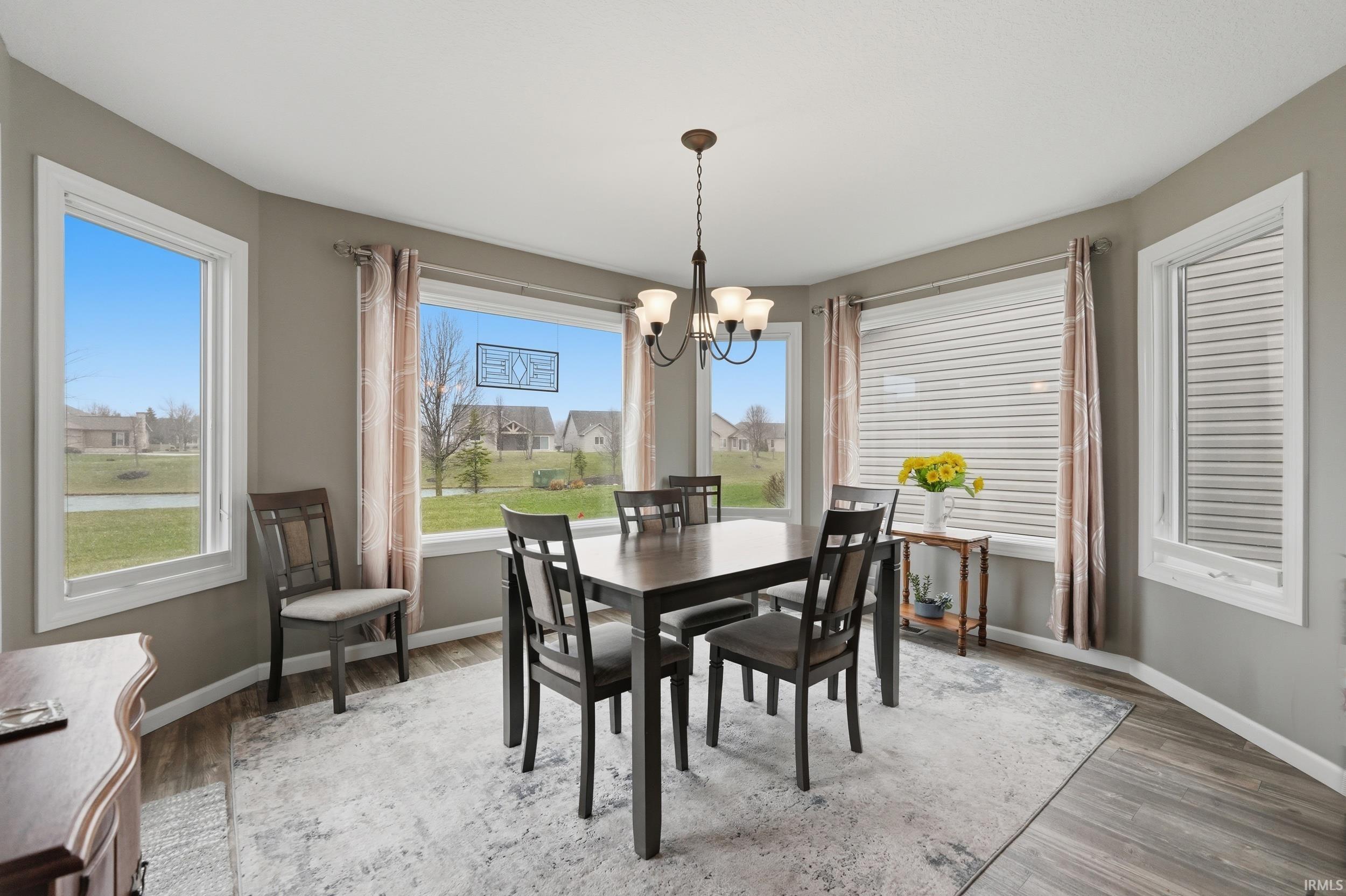 Dining room with hanging lights, light wood-style floors, and a residential view