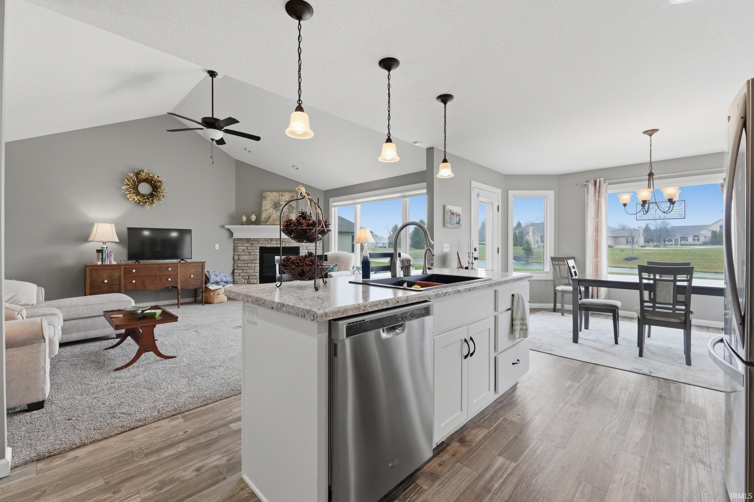 Kitchen featuring a fireplace, white cabinetry, stainless steel appliances, a kitchen island with sink, and open floor plan