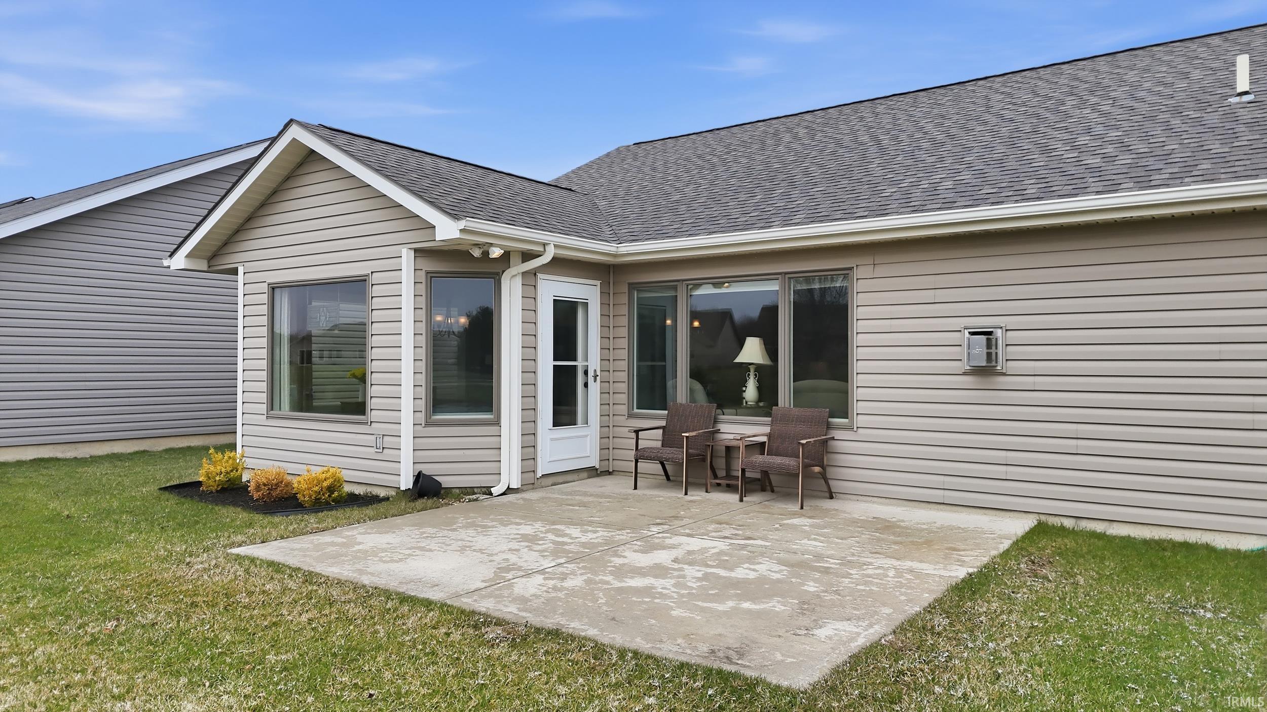 Rear view of property with a shingled roof, a yard, and a patio area
