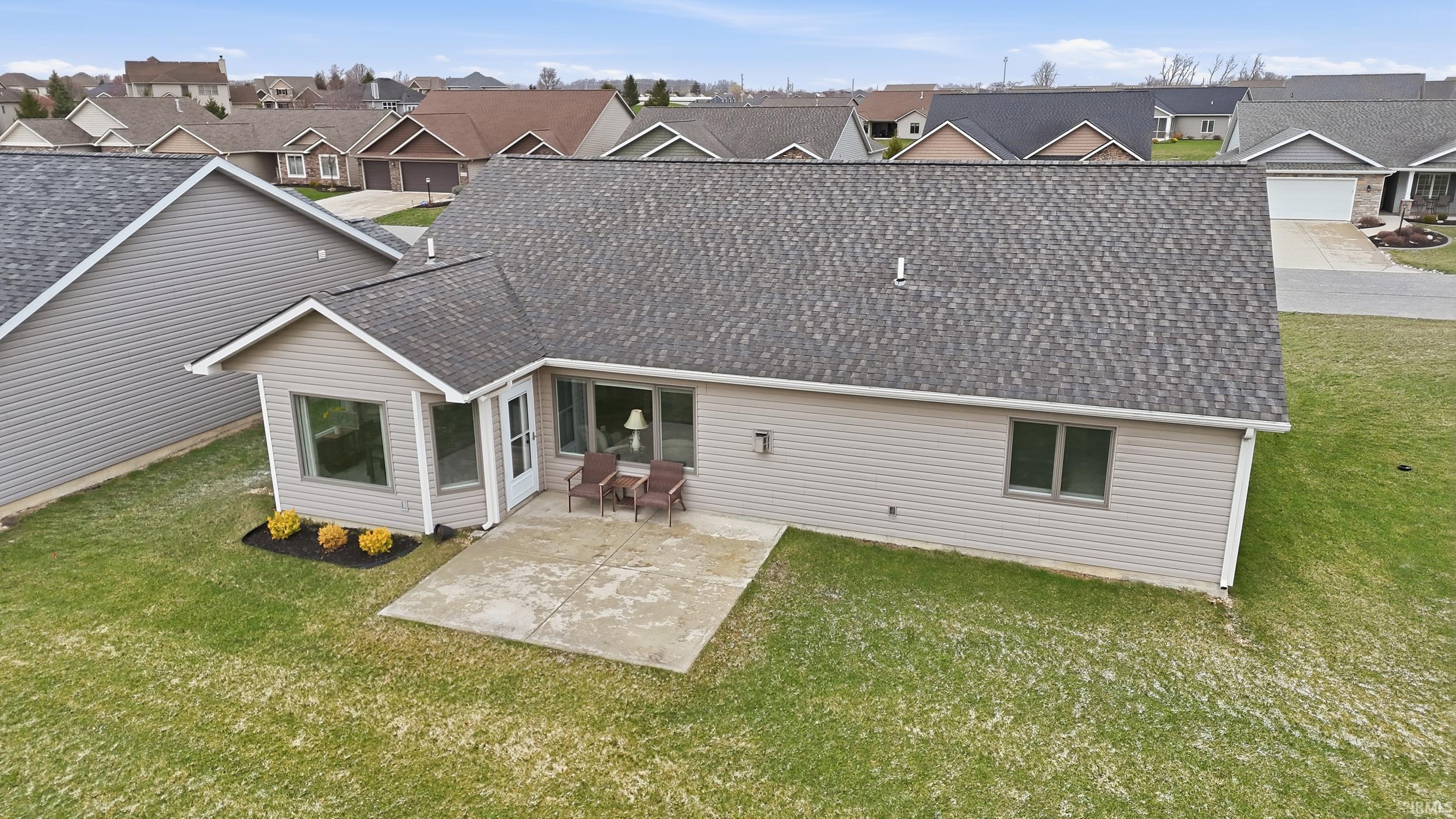 Back of property with a shingled roof, a patio, a yard, and a residential view