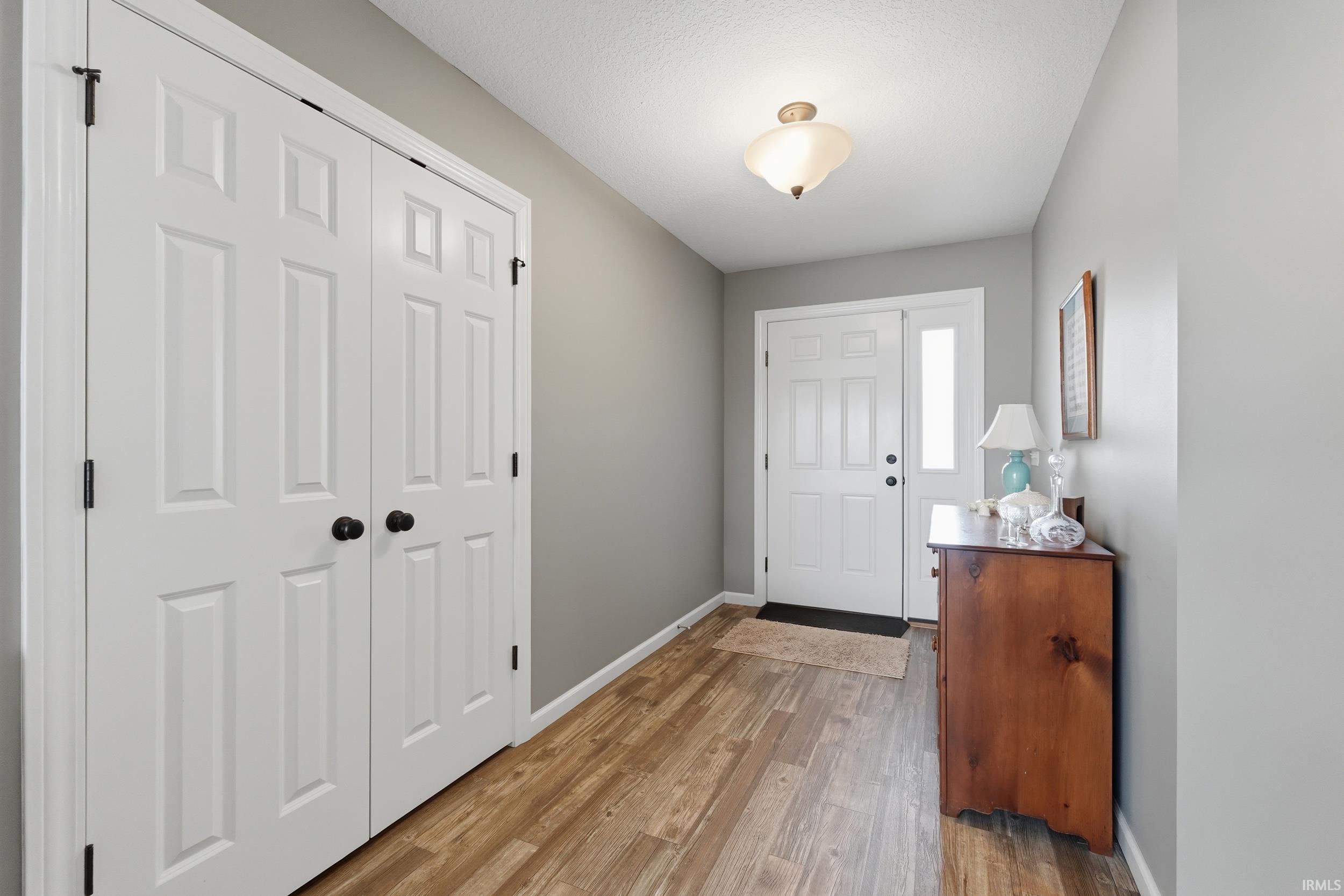 Foyer with light wood finished floors and a textured ceiling