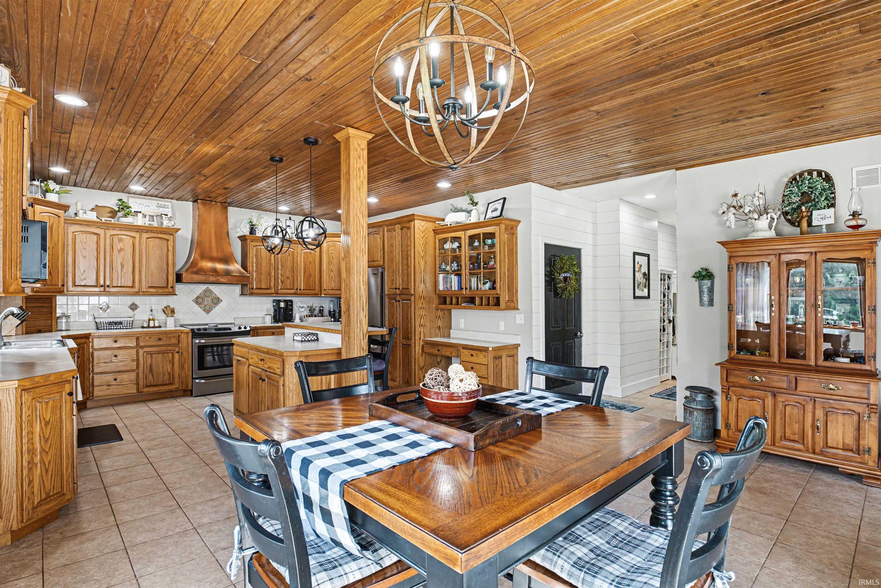 Dining space with suspended lighting, light tile patterned flooring, and wooden ceiling