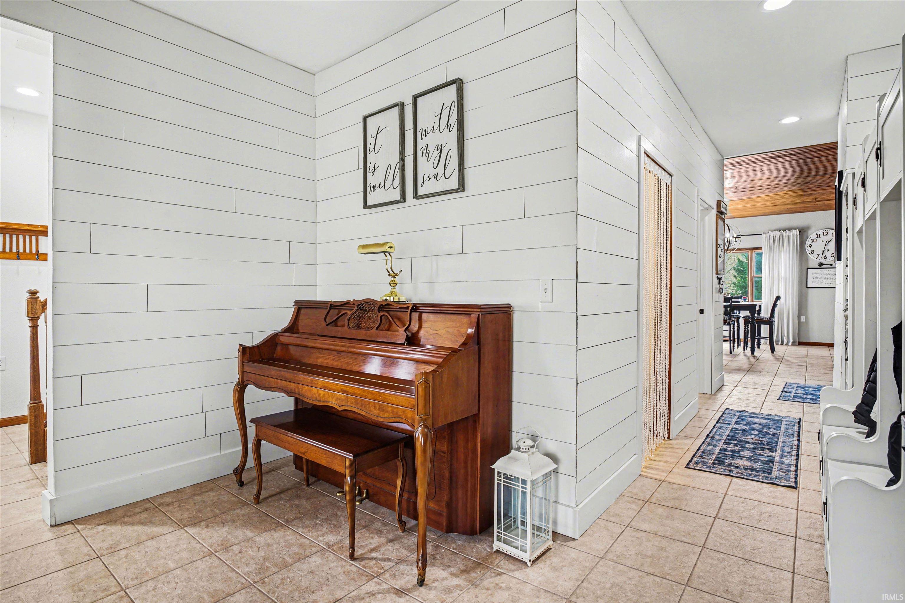 Hall featuring recessed lighting, light tile patterned flooring, and wooden walls