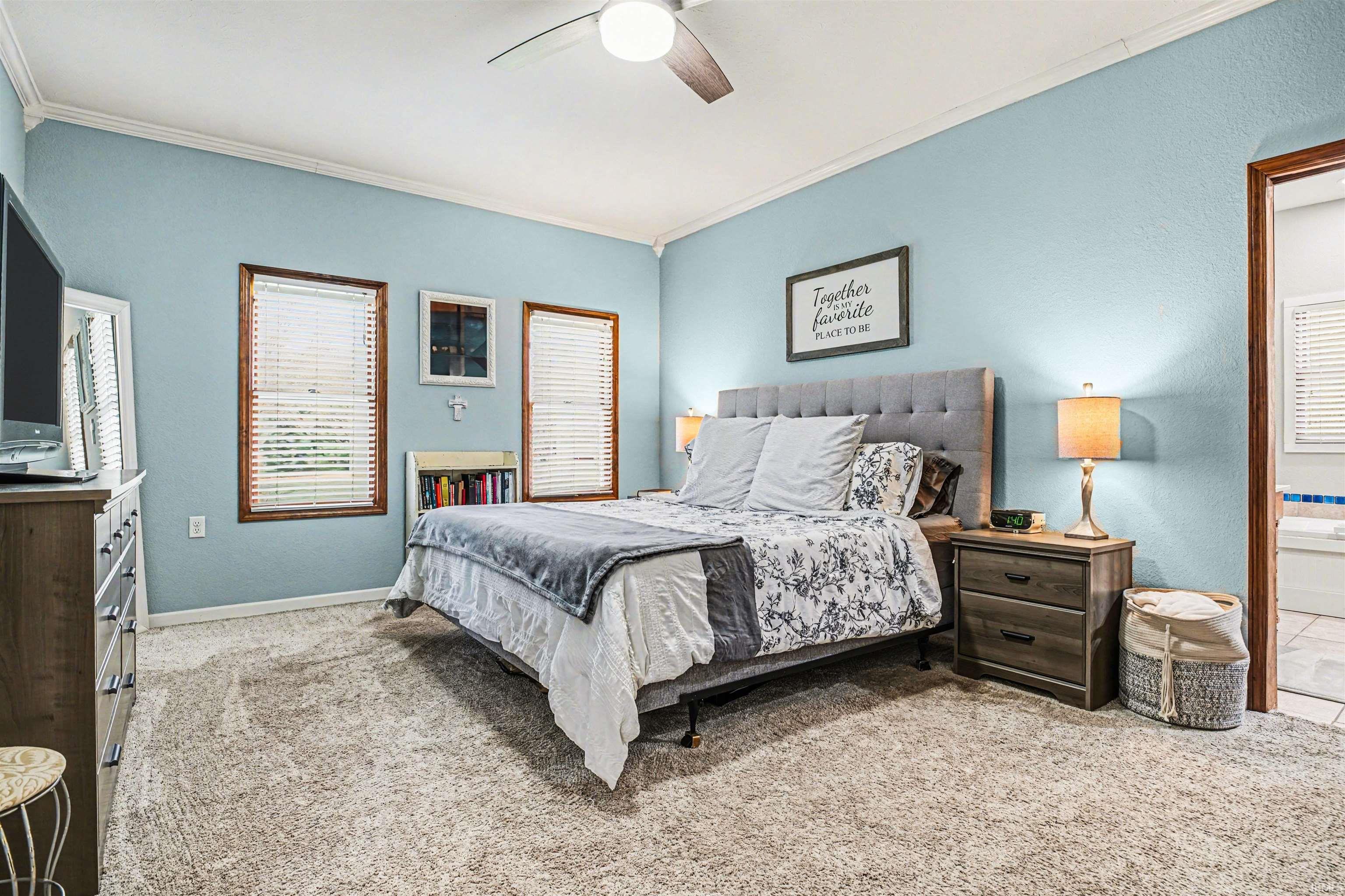 Bedroom featuring carpet flooring, crown molding, ceiling fan, and a textured wall