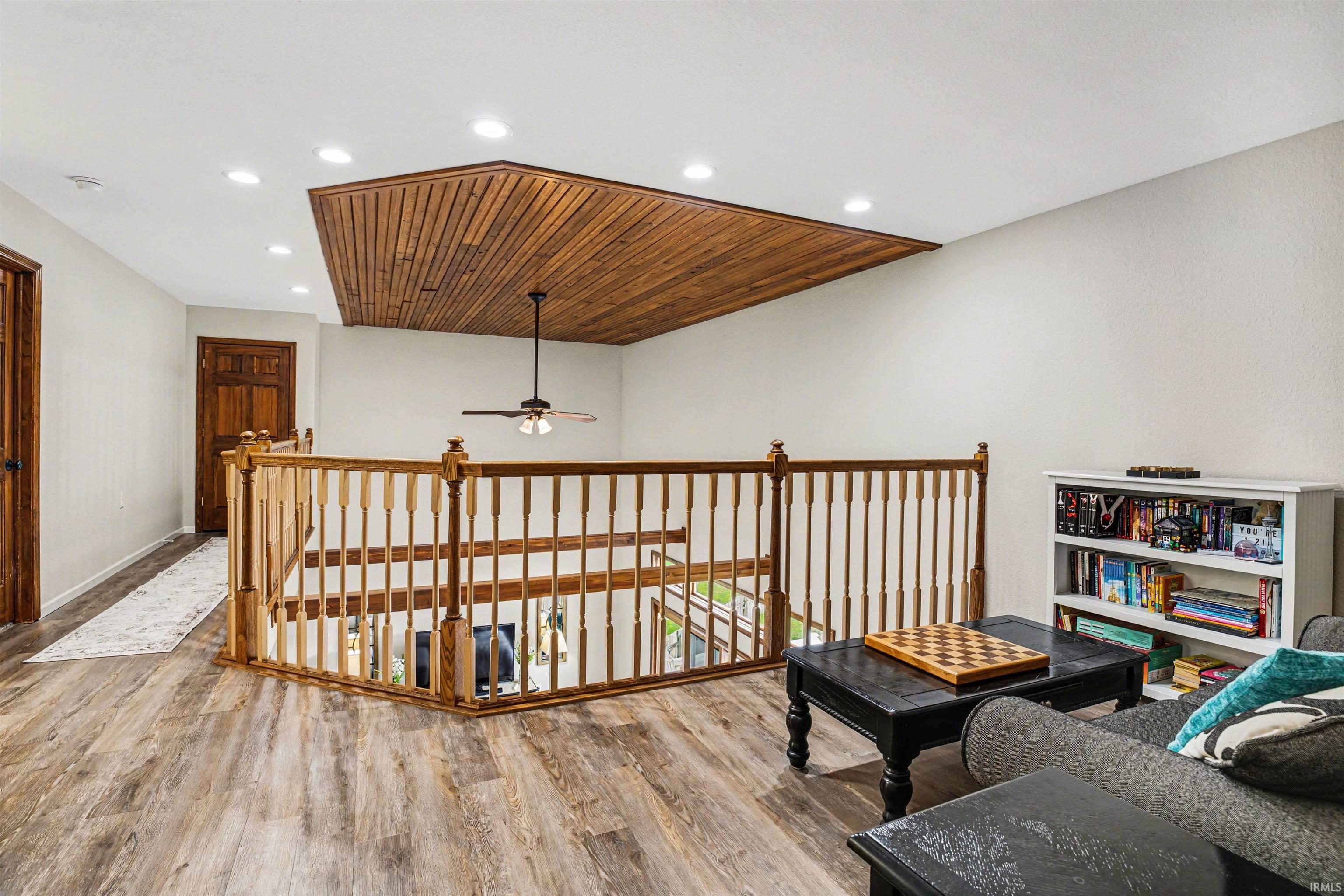 Sitting room with wood finished floors, recessed lighting, a ceiling fan, and an upstairs landing