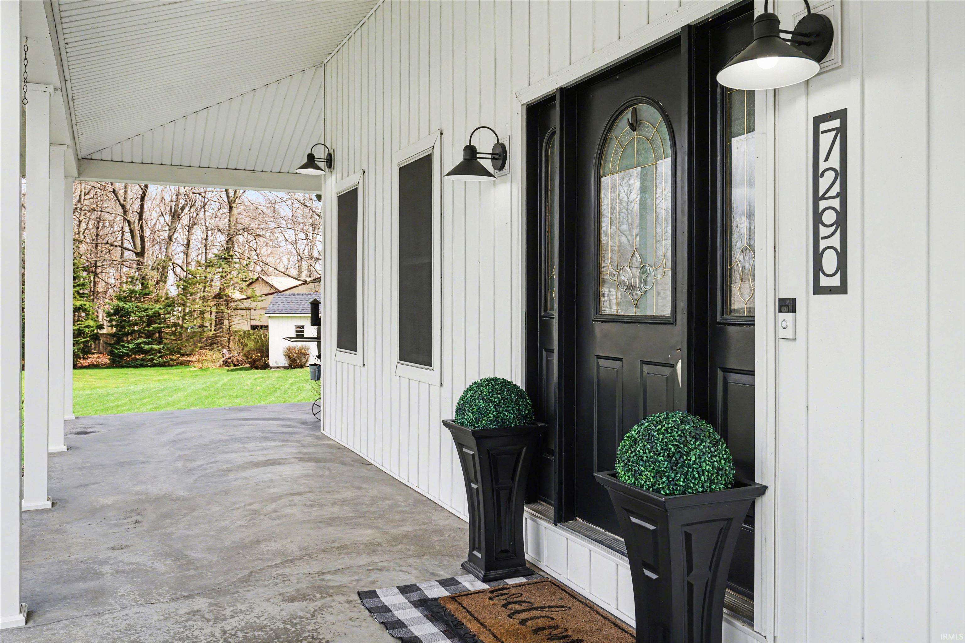 Doorway to property with a lawn and a patio
