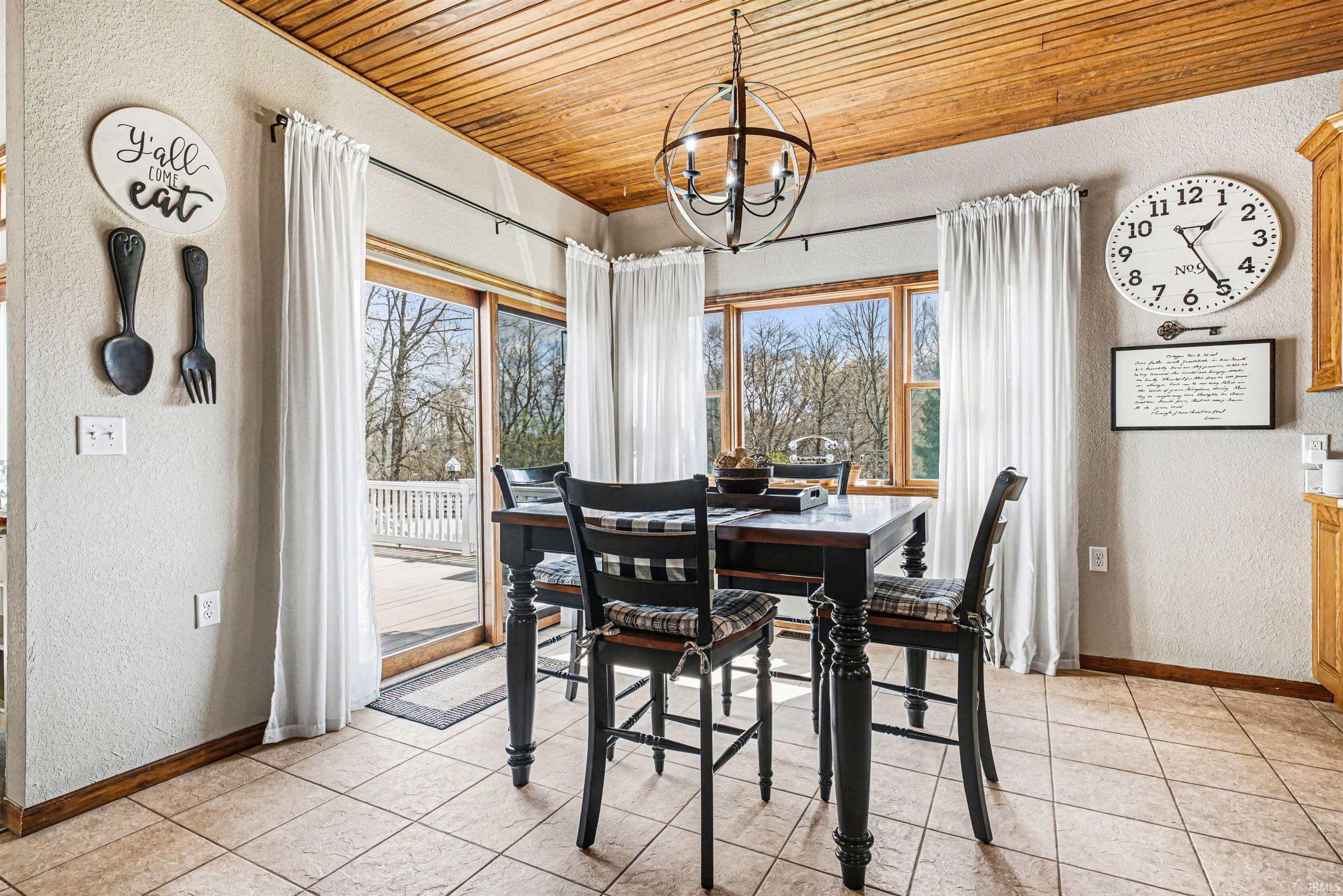 Dining area featuring a textured wall, wood ceiling, and hanging lights