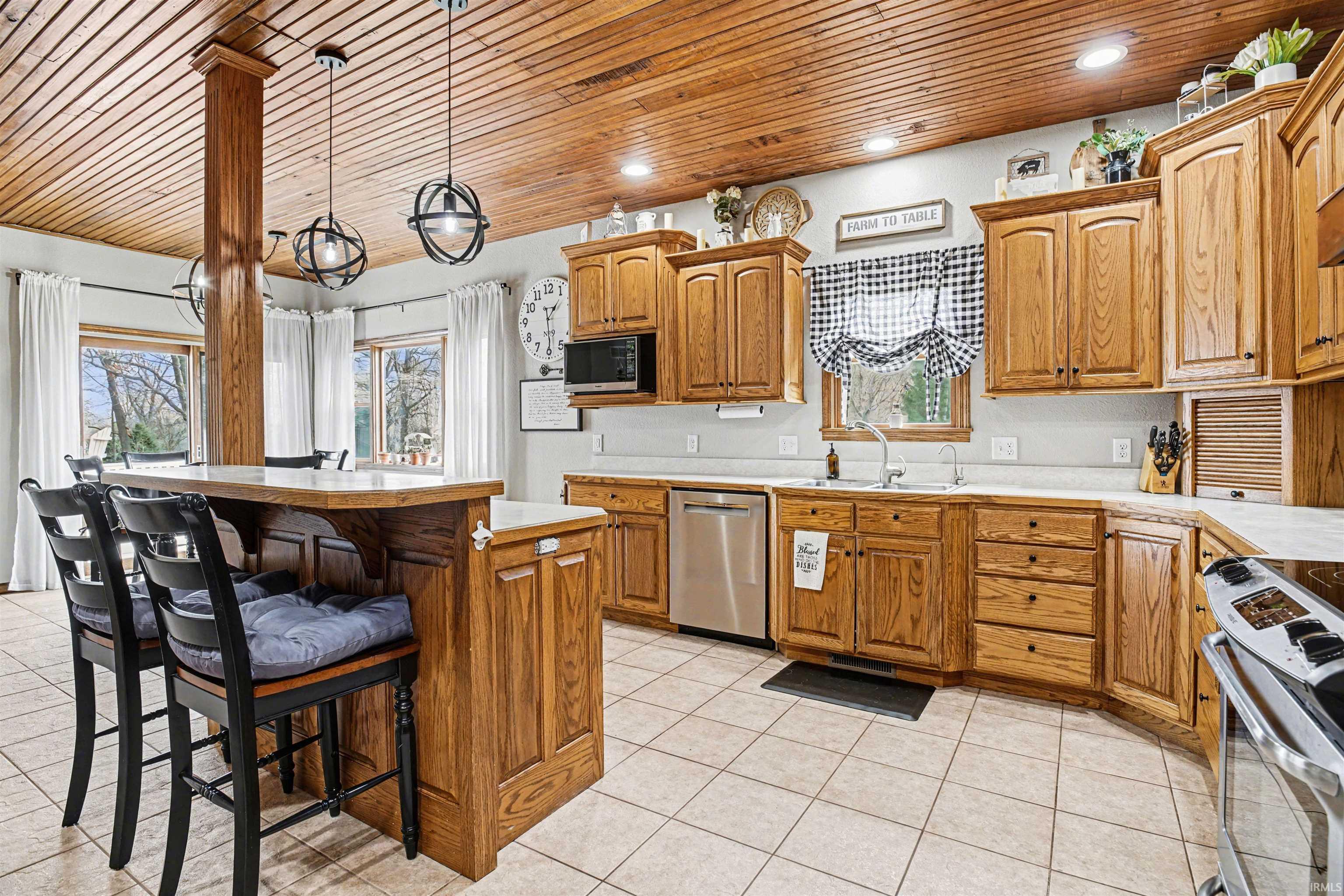 Kitchen with a breakfast bar, light countertops, stainless steel appliances, wood finish cabinets, and wooden ceiling