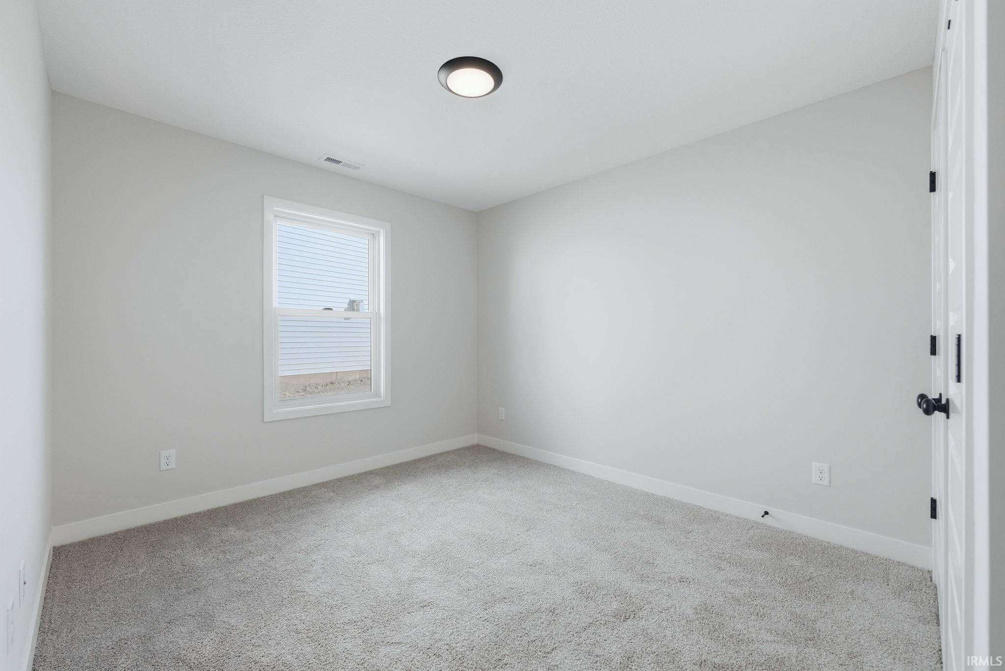 Spare room featuring light colored carpet and baseboards