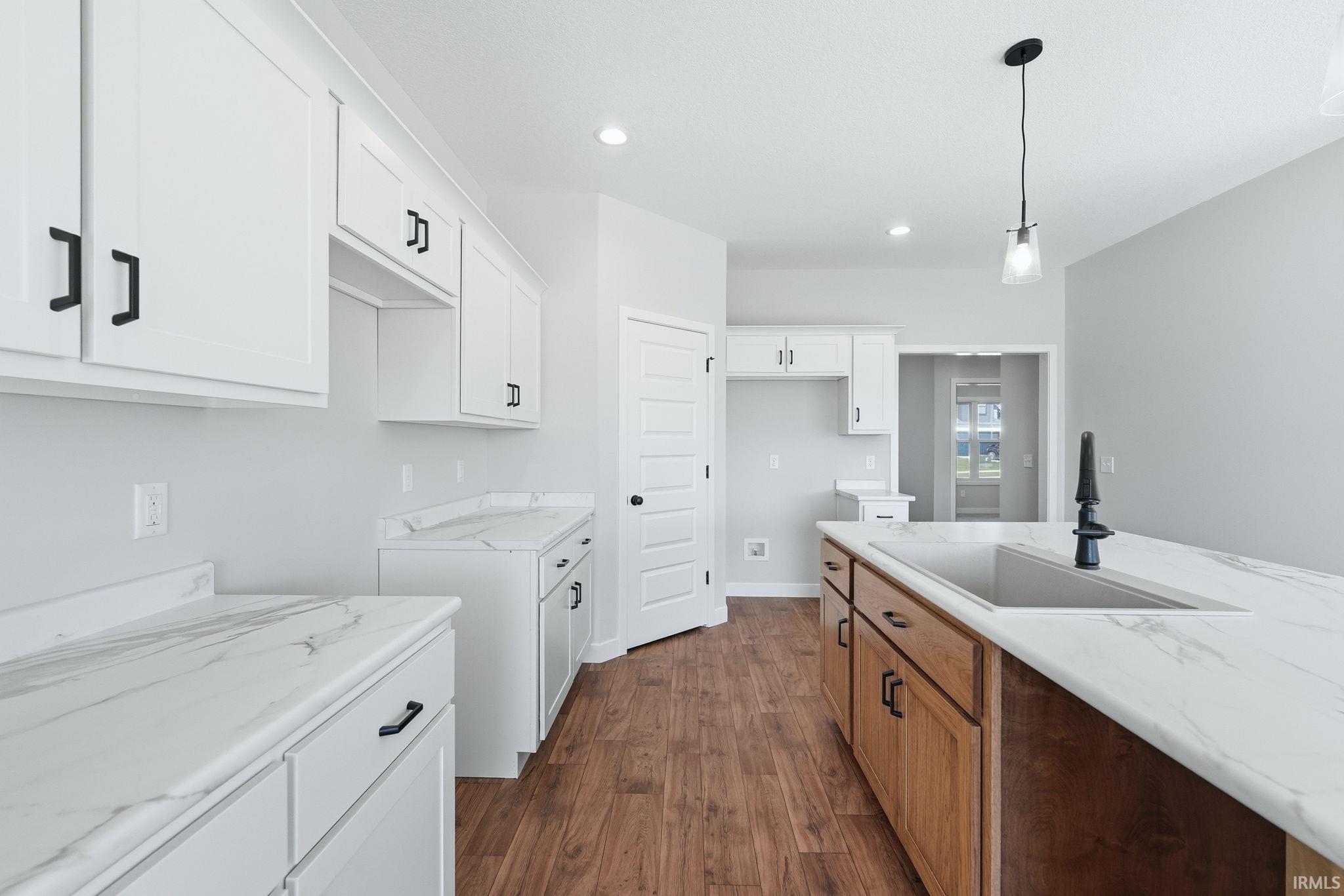 Dual tone kitchen featuring dual tone cabinets, dark wood-type flooring, and pendant lighting