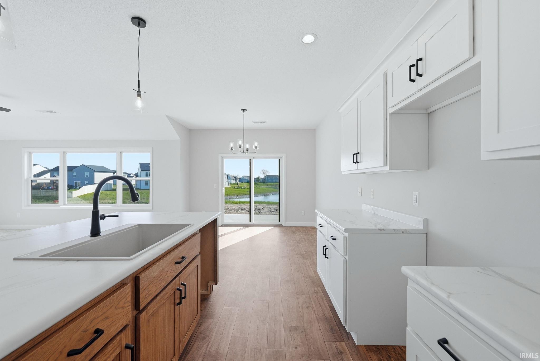 Kitchen featuring dark wood finished floors, two tone cabinets, and a chandelier