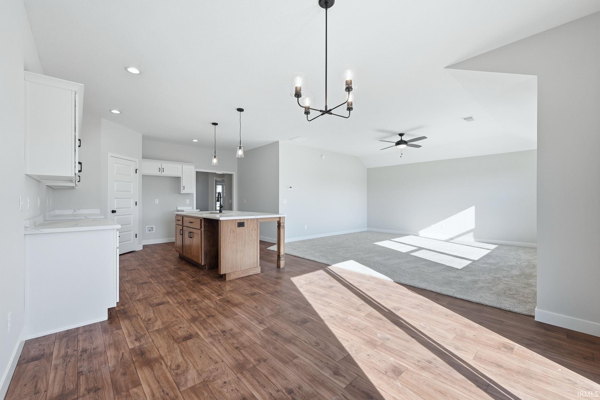 Kitchen with hanging lights, open floor plan, a center island with sink, two tone cabinets, and dark wood-style flooring