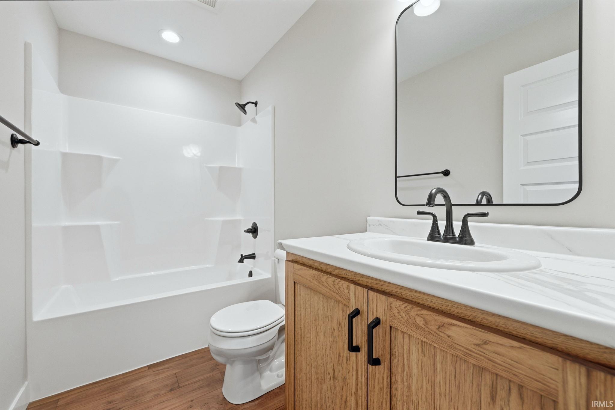 Bathroom with vanity,  shower combination, wood finished floors, and recessed lighting