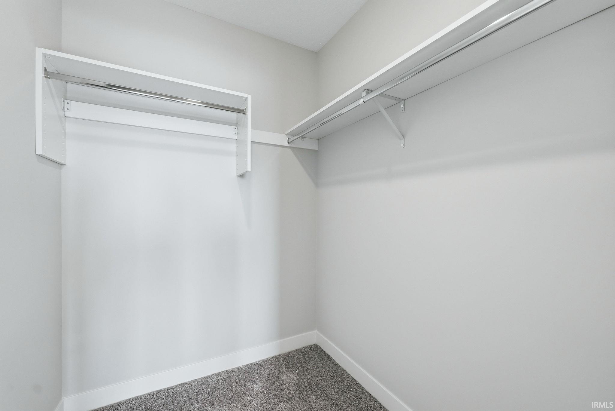 Walk in closet with dark colored carpet