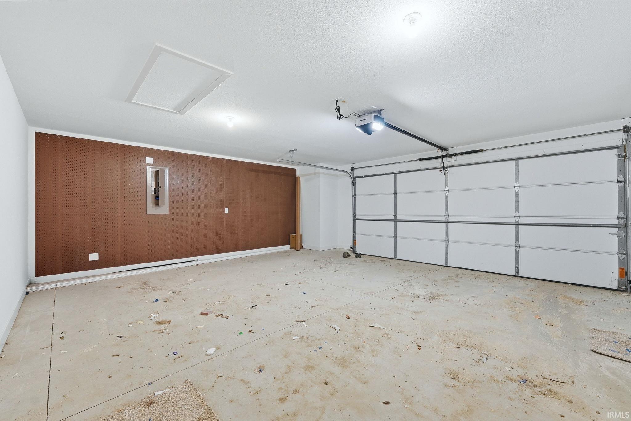 Garage with electric panel, wood walls, and a garage door opener
