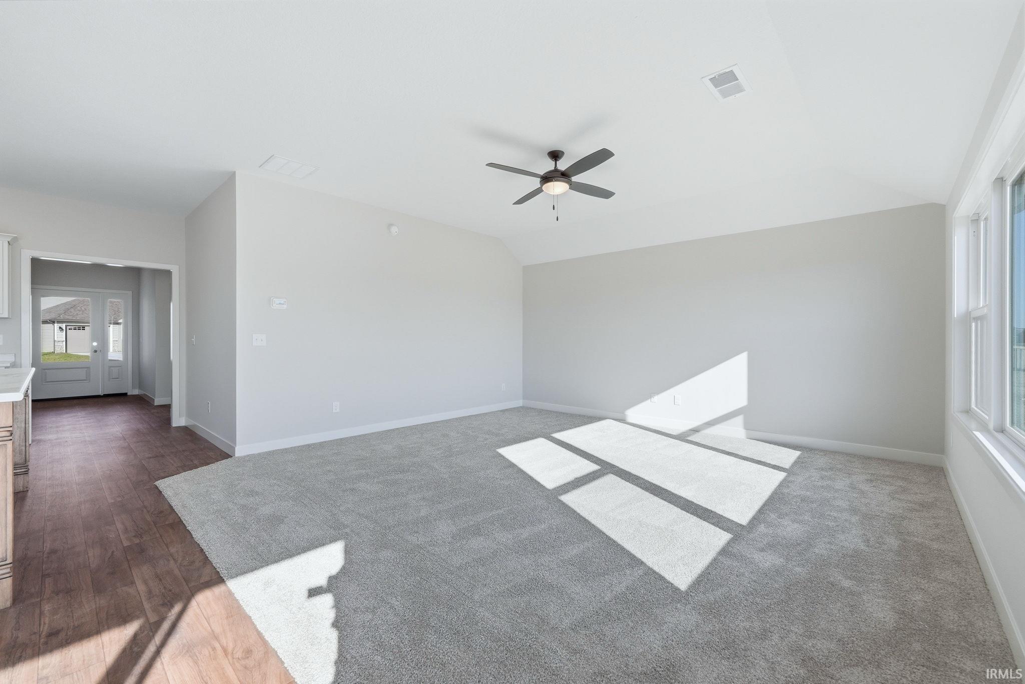 Unfurnished living room with vaulted ceiling, a ceiling fan, and dark wood finished floors
