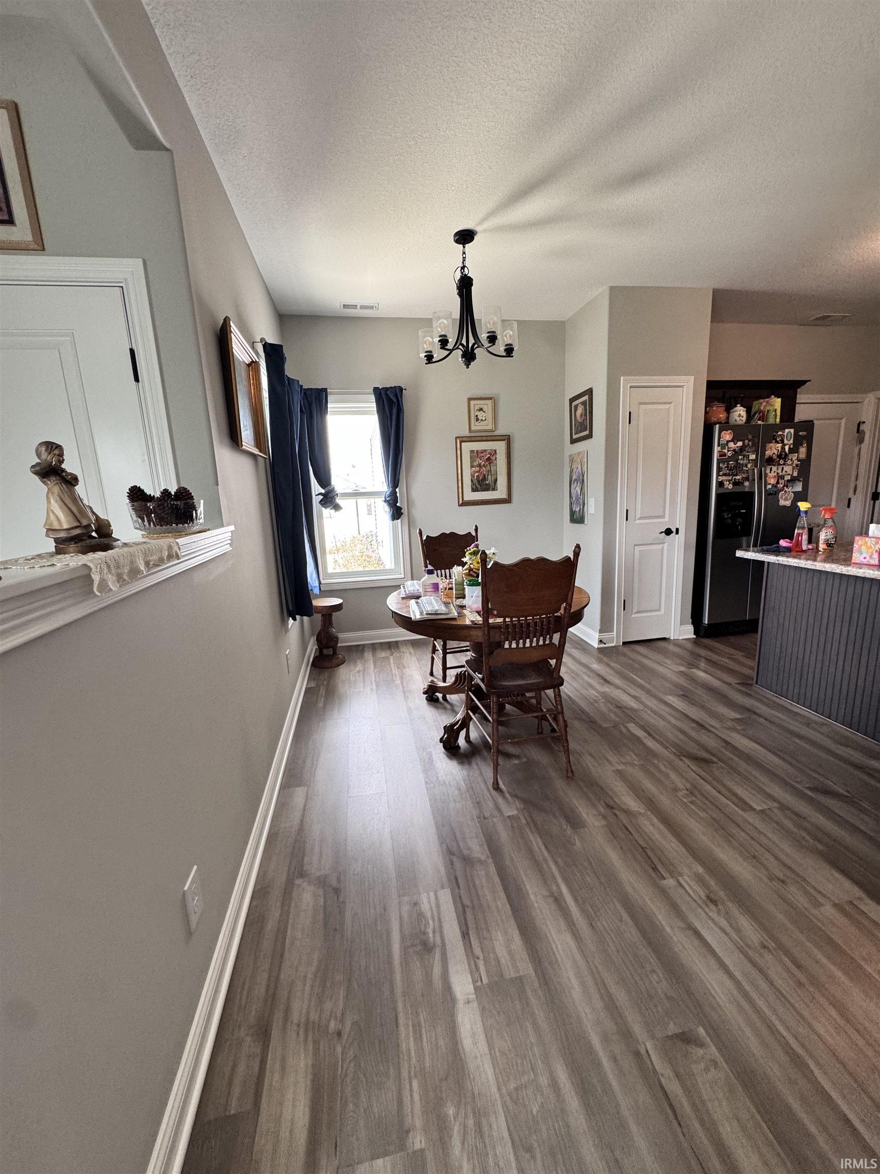 Dining area featuring dark wood finished floors, a textured ceiling, and a chandelier