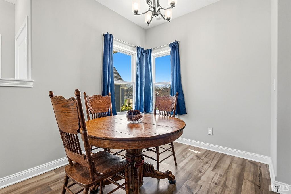Corner window alcove with wood-finish flooring, light gray walls, and white baseboards