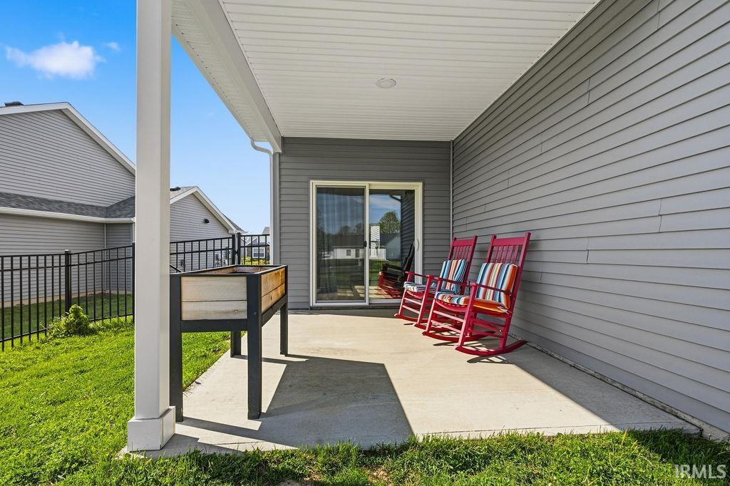 Covered patio featuring a concrete slab, white column, and gray vinyl siding