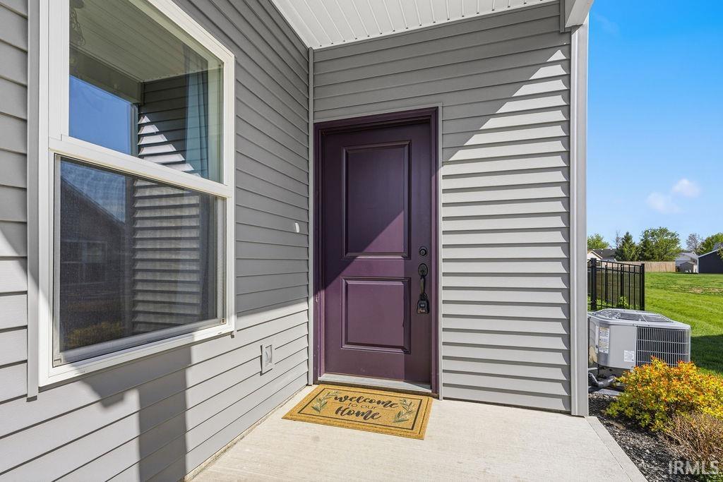 Entryway featuring a paneled purple door, light gray horizontal siding, and a white-framed window