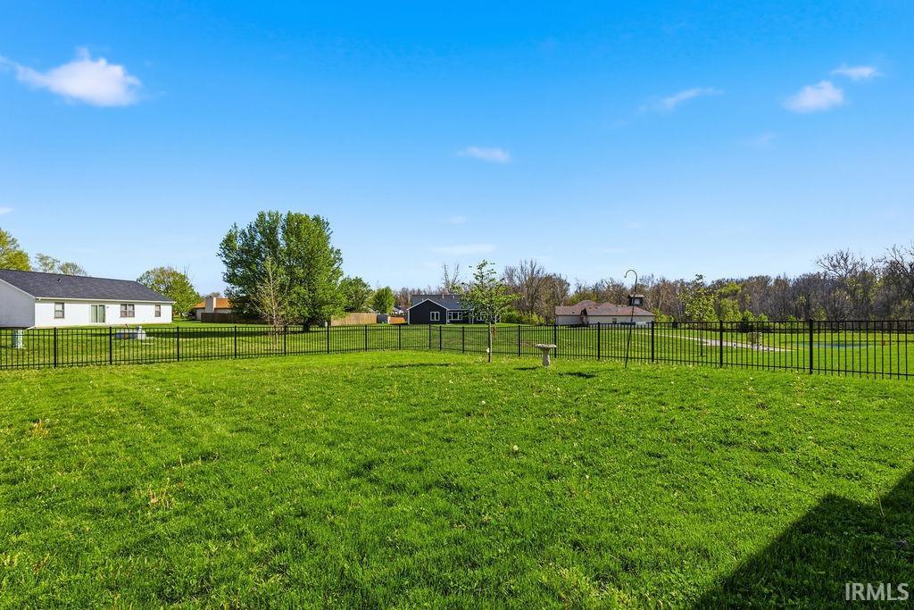 Expansive green lawn featuring a full black metal fence enclosure