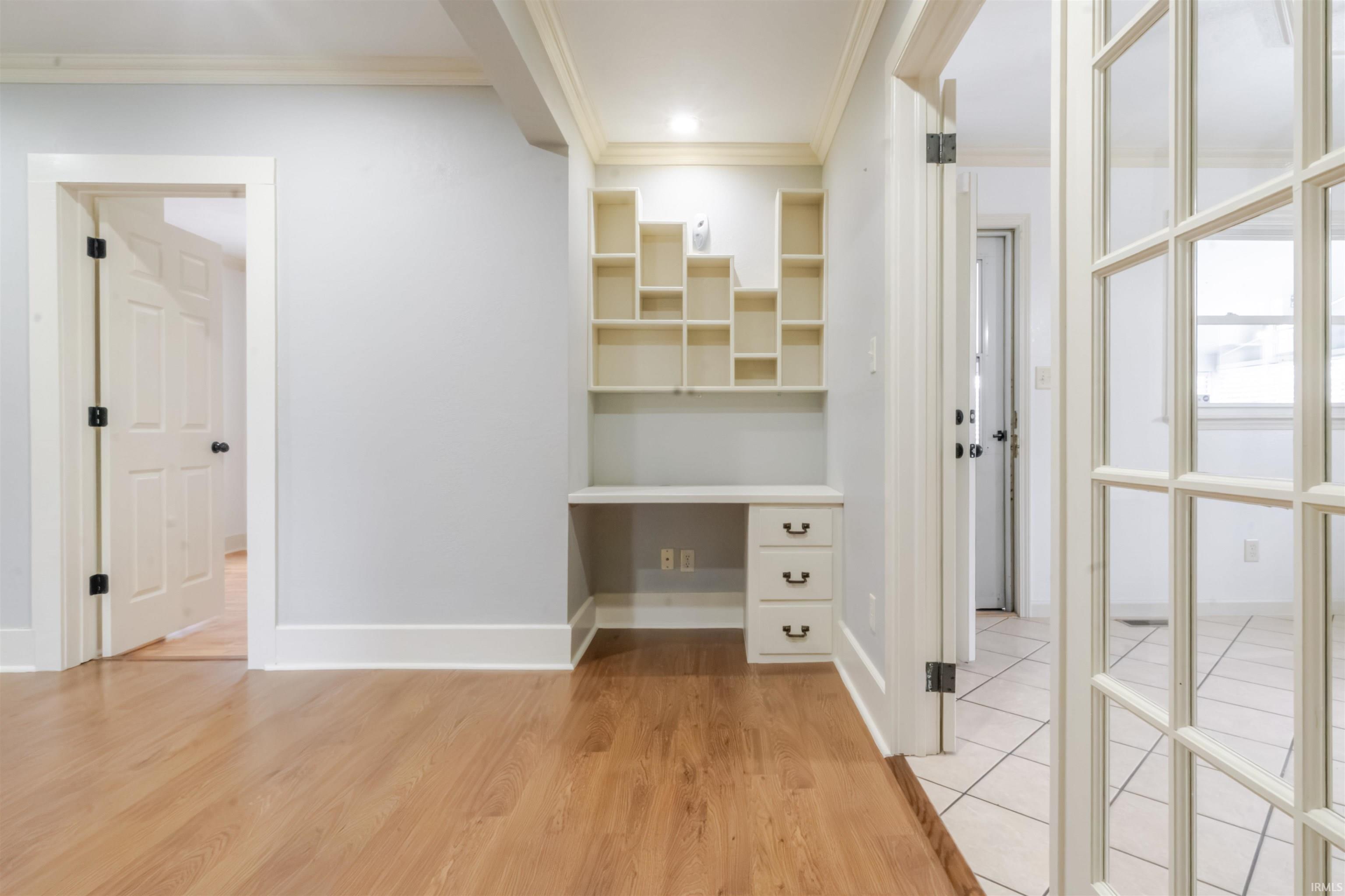 Hallway featuring a desk, light wood-type flooring, and ornamental molding