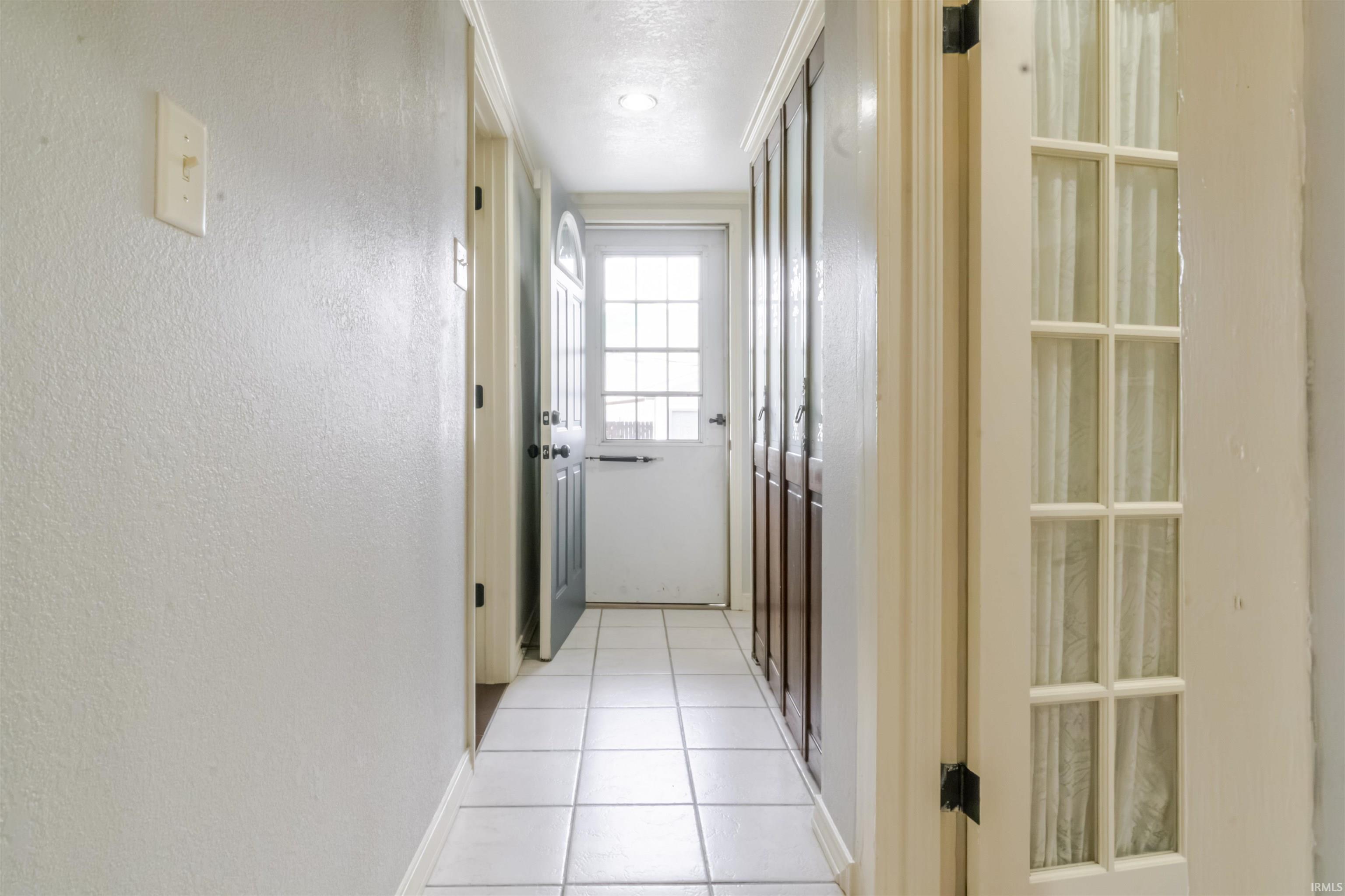 Hallway featuring a textured wall and light tile patterned floors
