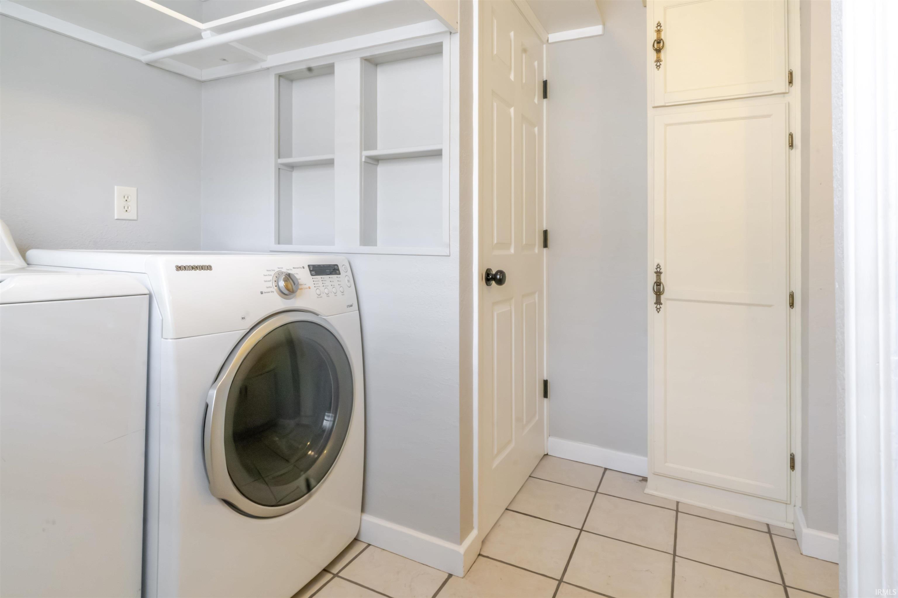 Laundry room featuring light tile patterned floors and washing machine and clothes dryer
