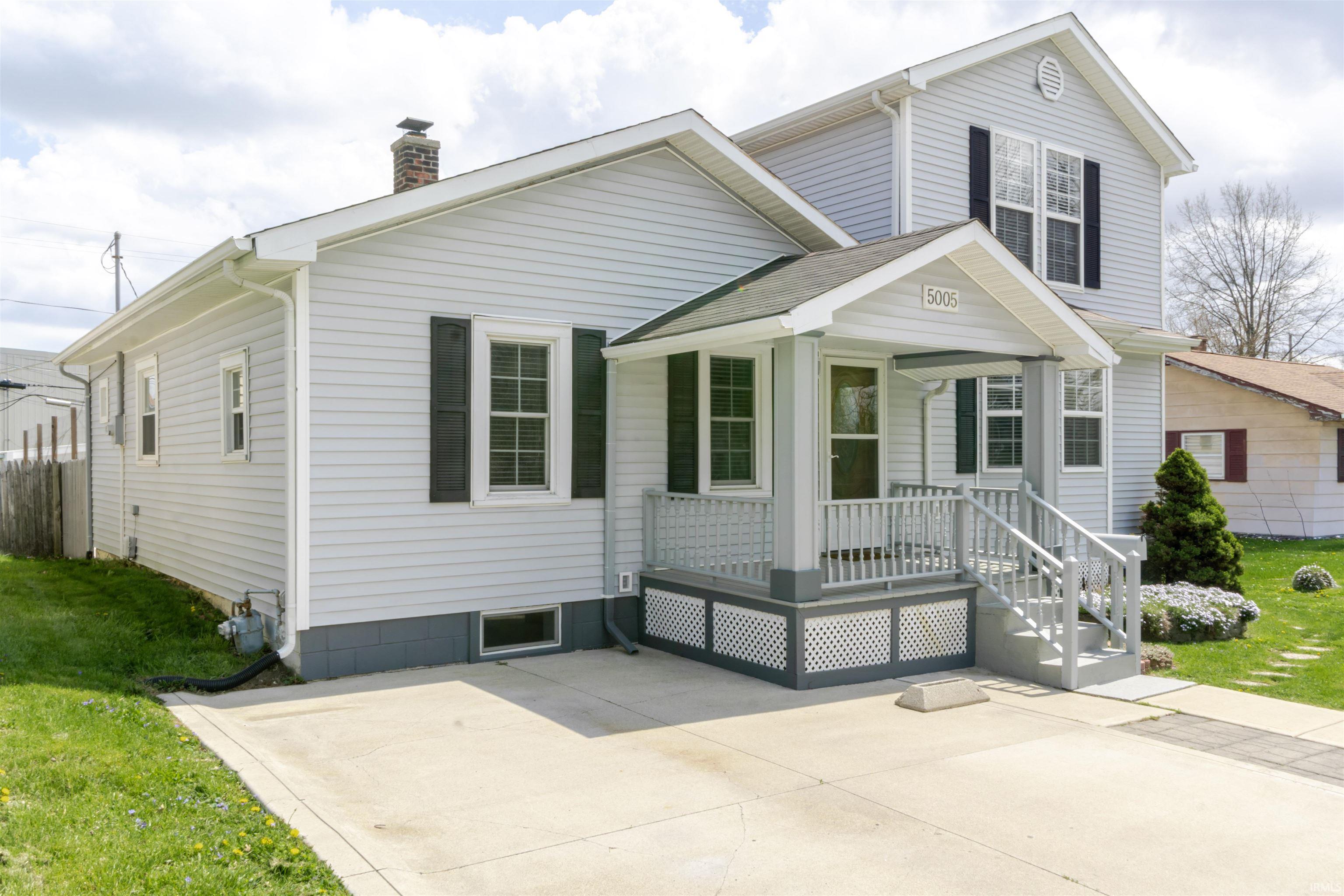 View of front of home featuring a front yard, a chimney, a porch, and a shingled roof