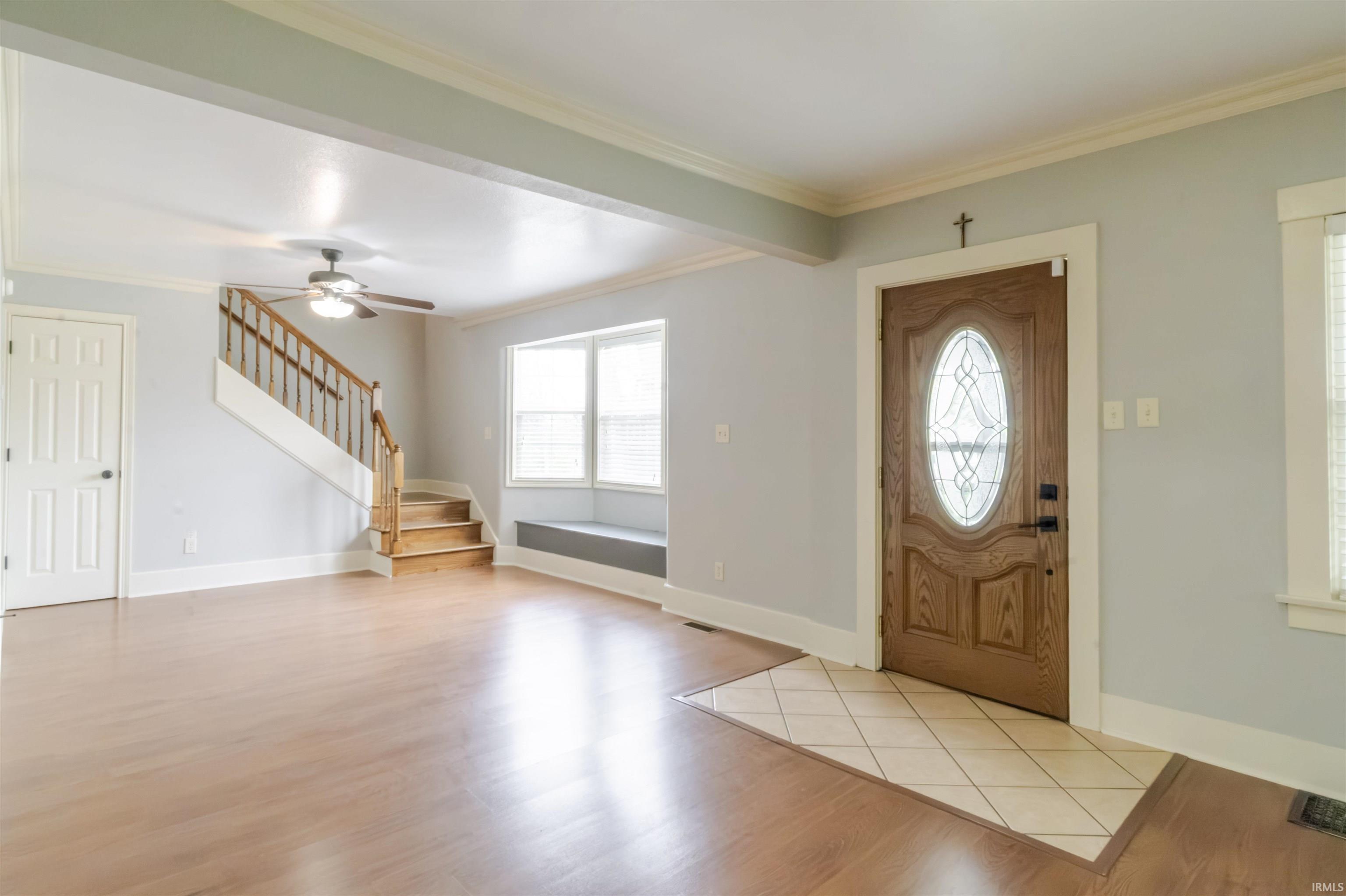 Entryway with ornamental molding, light wood-style flooring, and a ceiling fan