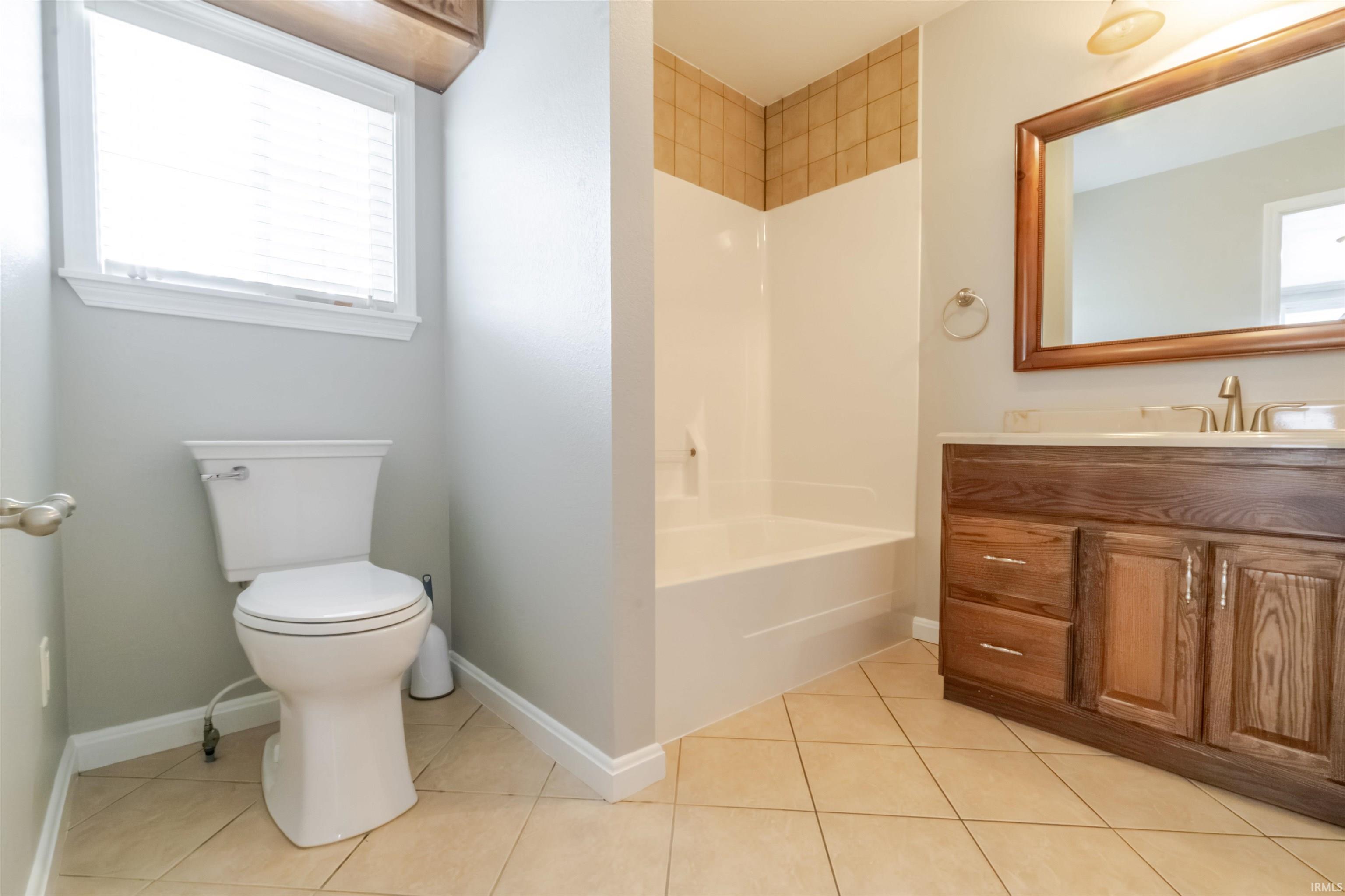 Bathroom with vanity, light tile patterned floors, and tub / shower combination