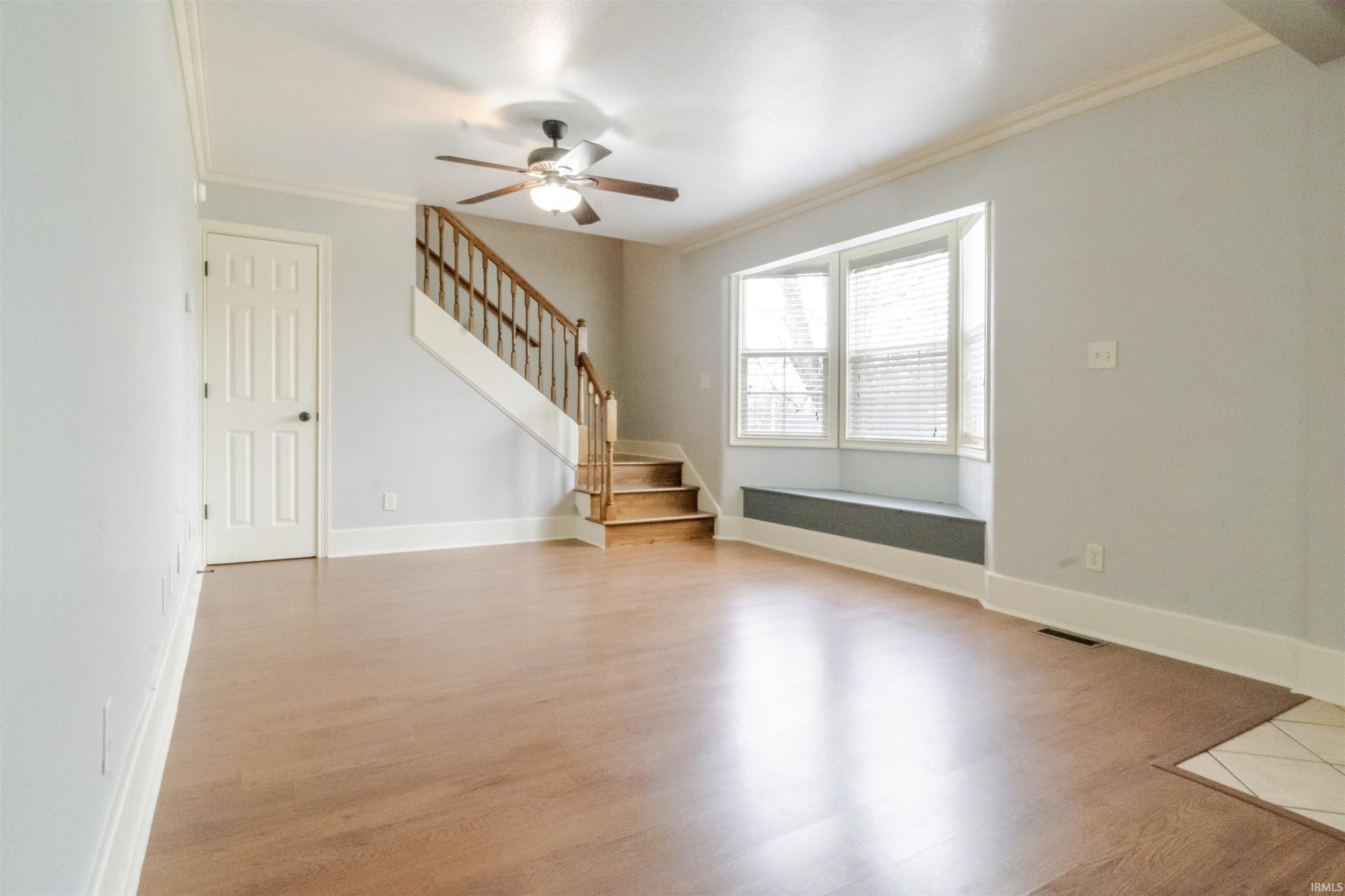 Unfurnished living room with ornamental molding, ceiling fan, and light wood finished floors