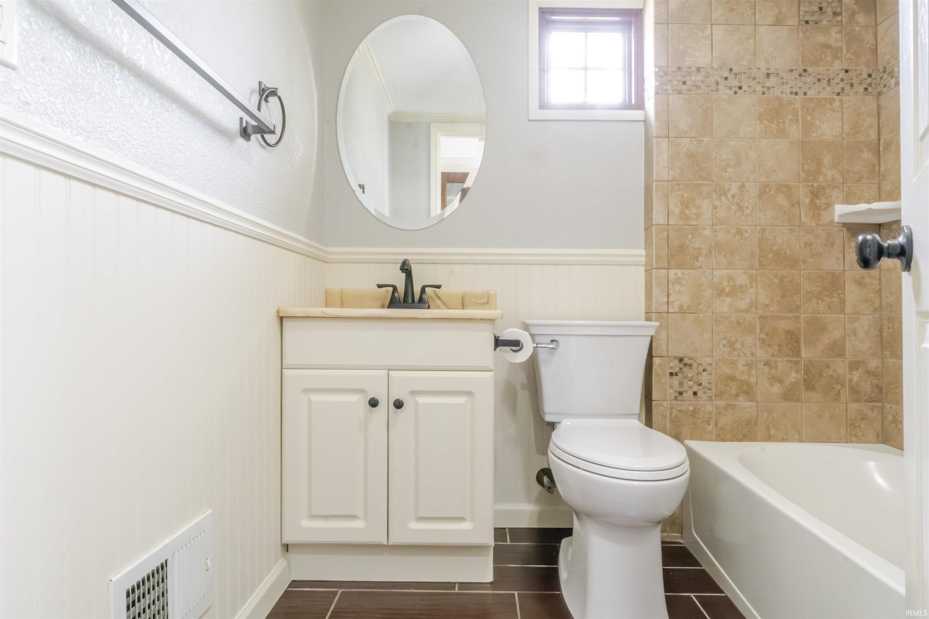 Full bath with vanity, wainscoting, and shower / bath combination