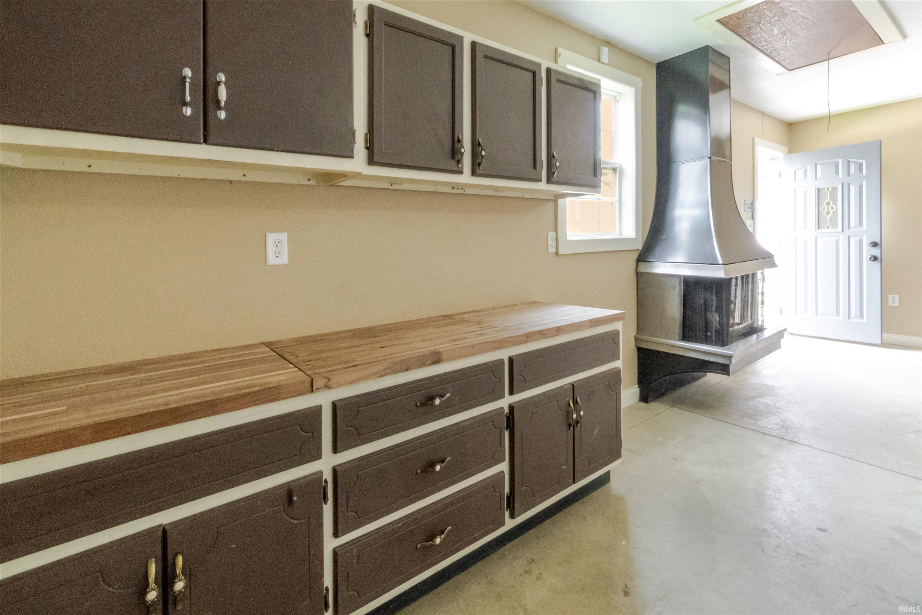 Kitchen featuring wooden counters, concrete flooring, and dark wood finish cabinets