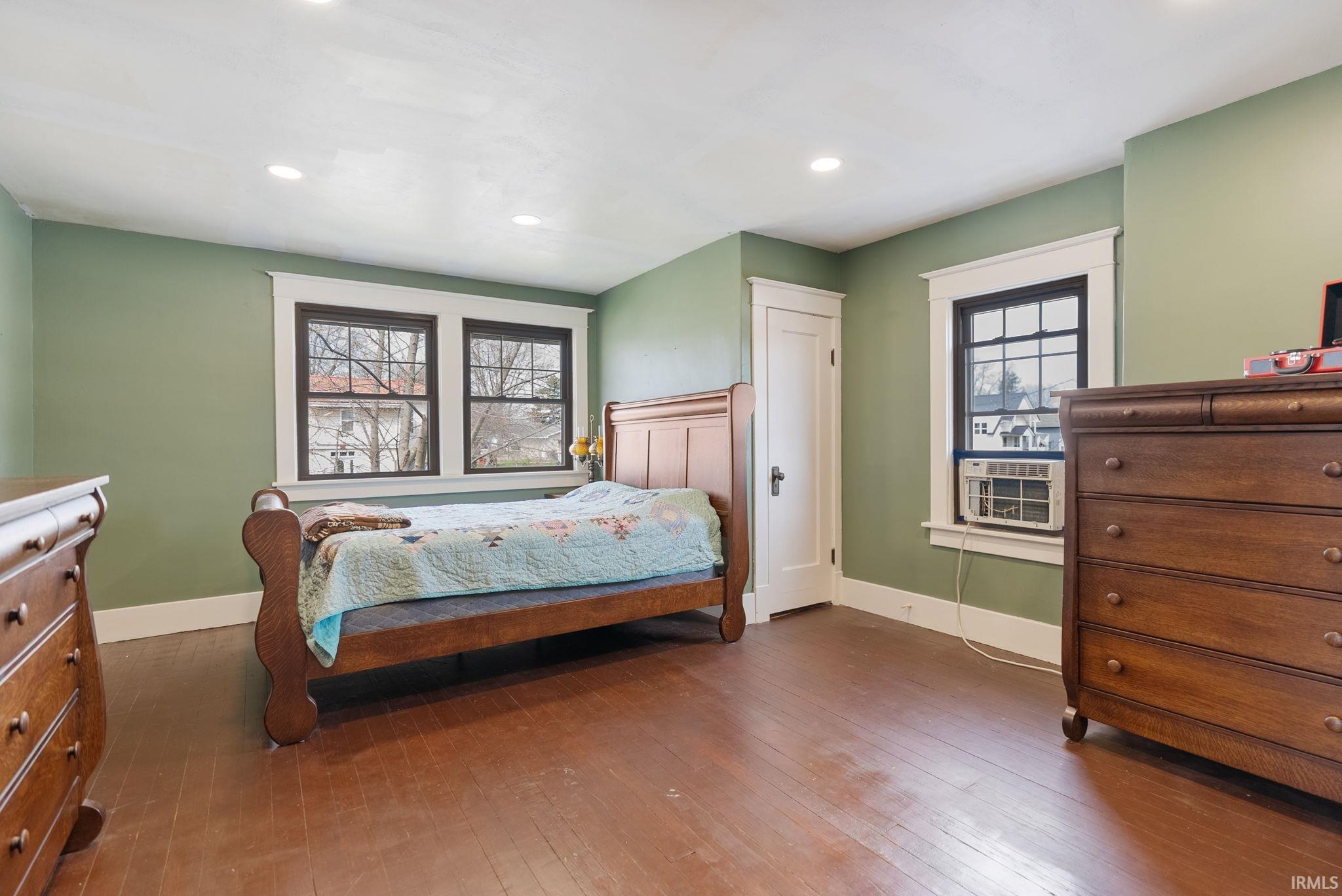 Bedroom with dark wood-style floors, multiple windows, and recessed lighting