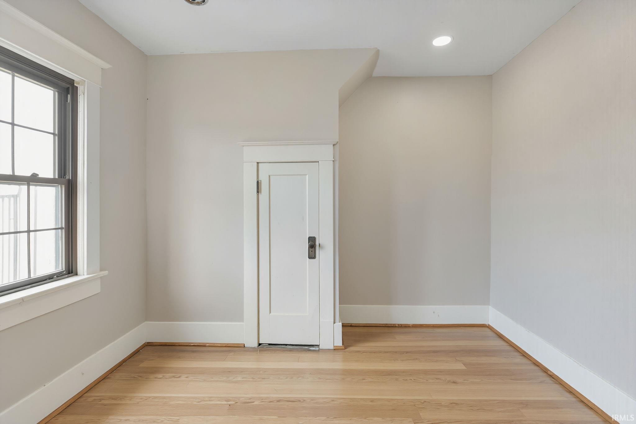 Empty room with light wood-style flooring and recessed lighting