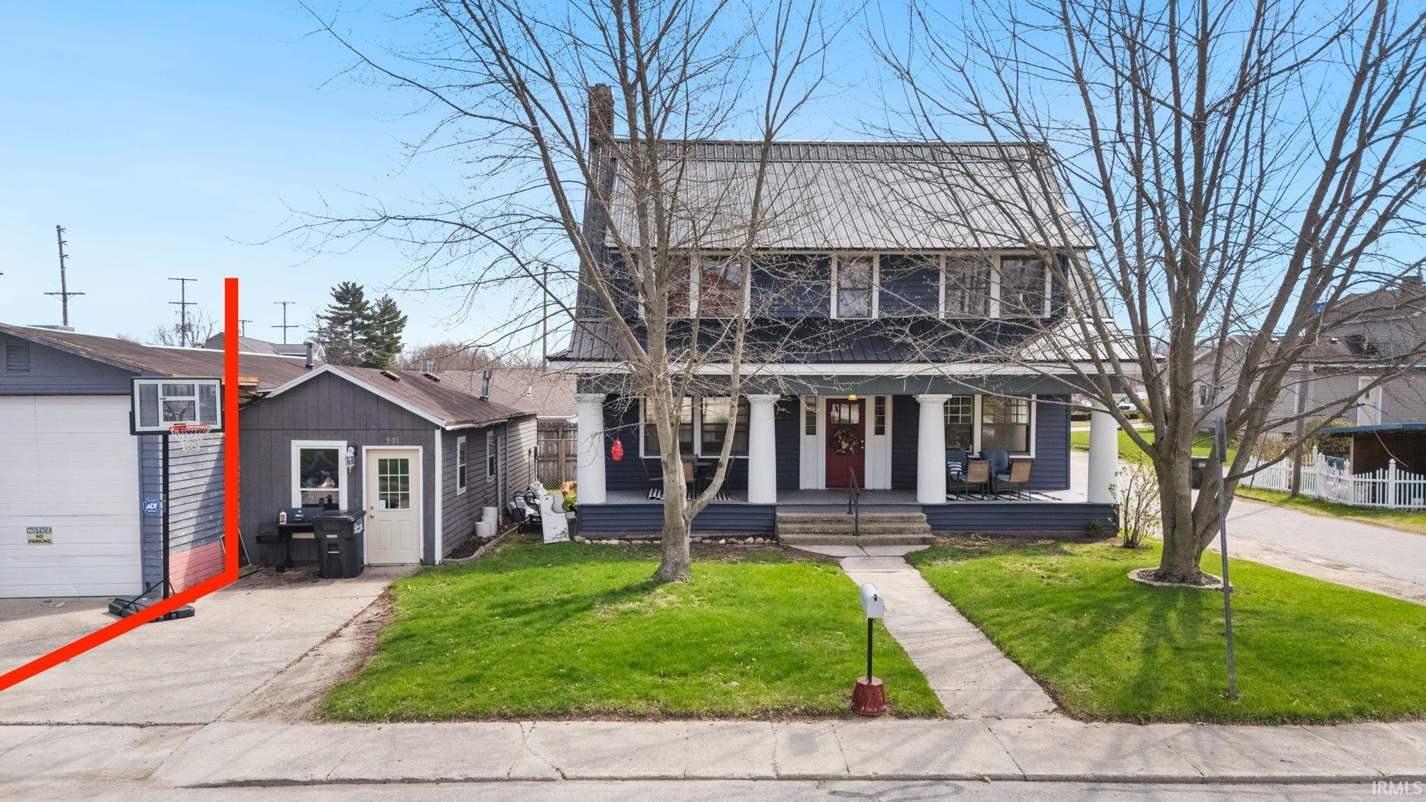 View of front of property featuring a porch, a front lawn, and an outbuilding