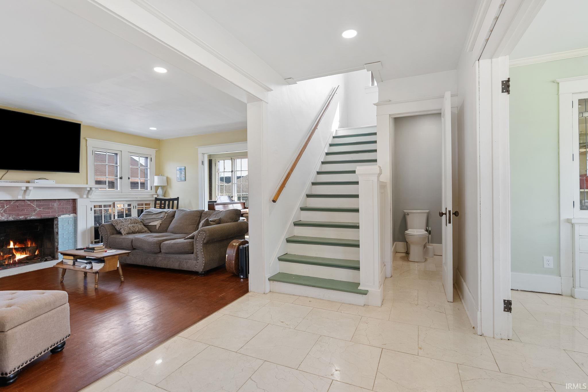 Living area with recessed lighting, a lit fireplace, and ornamental molding