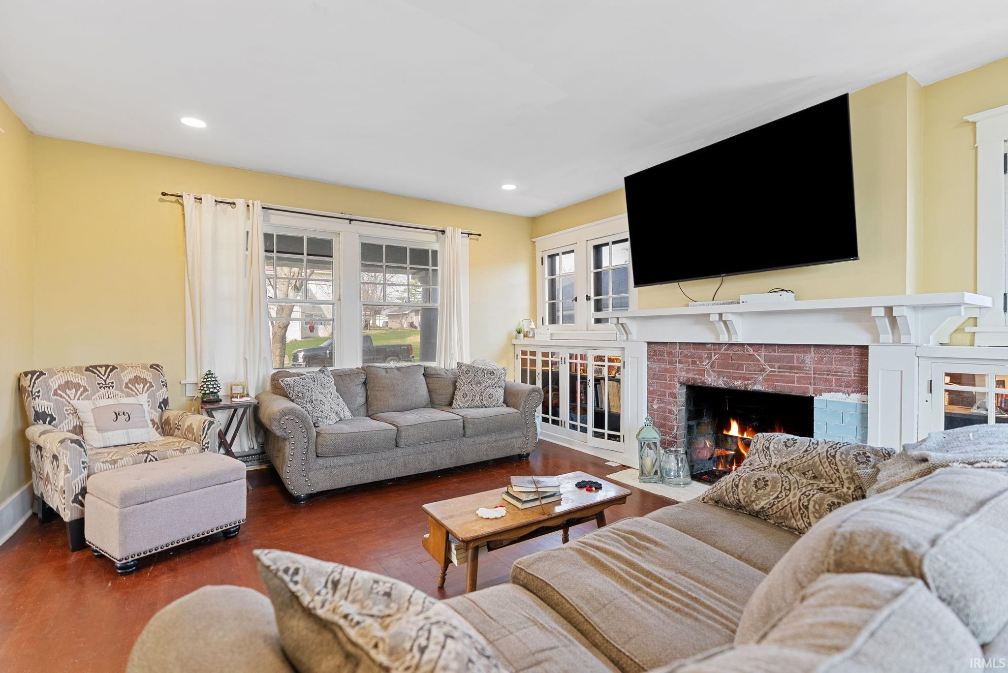 Living room with a brick fireplace, recessed lighting, and wood finished floors