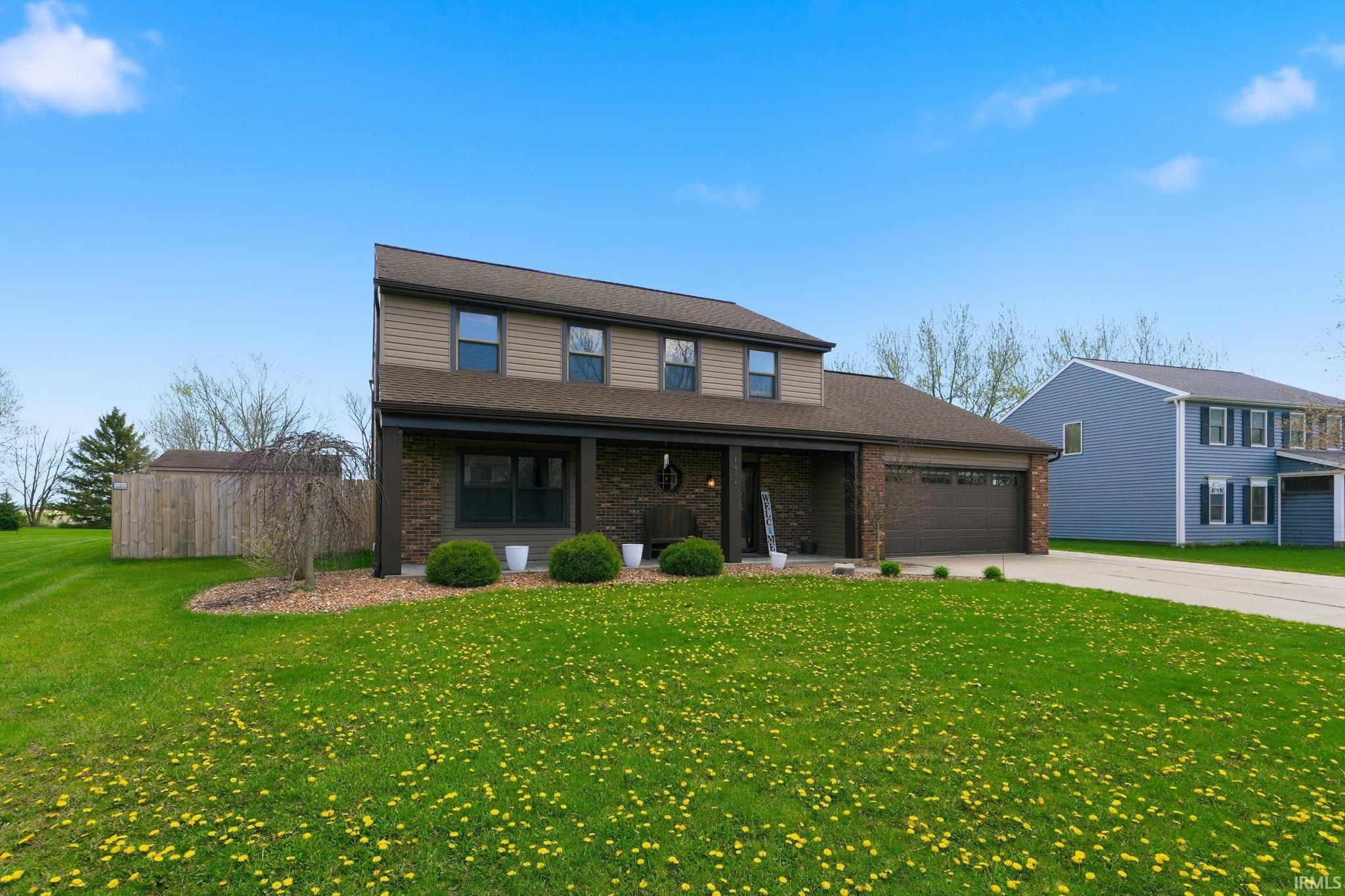 Traditional-style house with brick siding, a garage, and a front lawn
