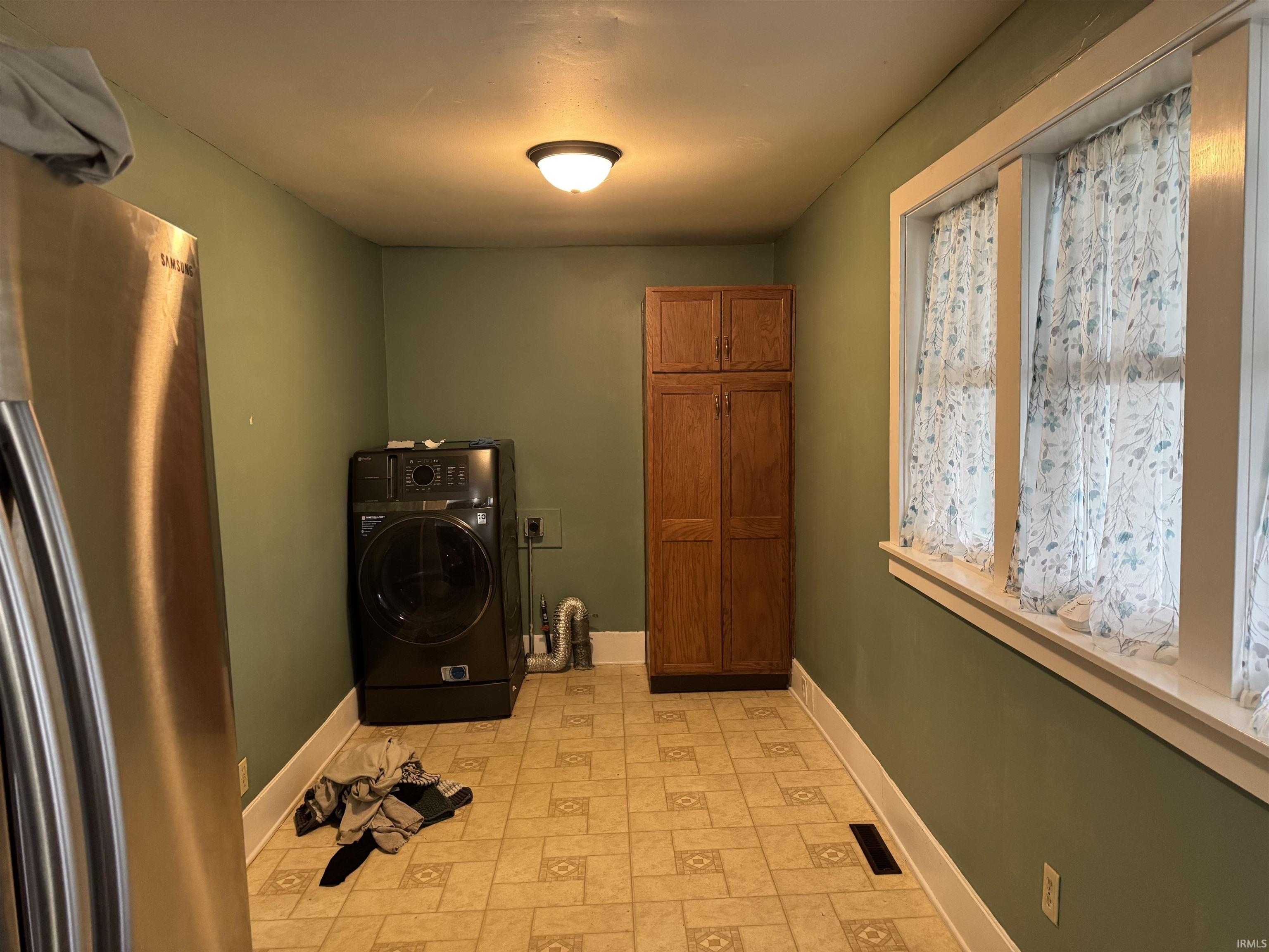 Laundry room with washer / clothes dryer, cabinet space, and light floors