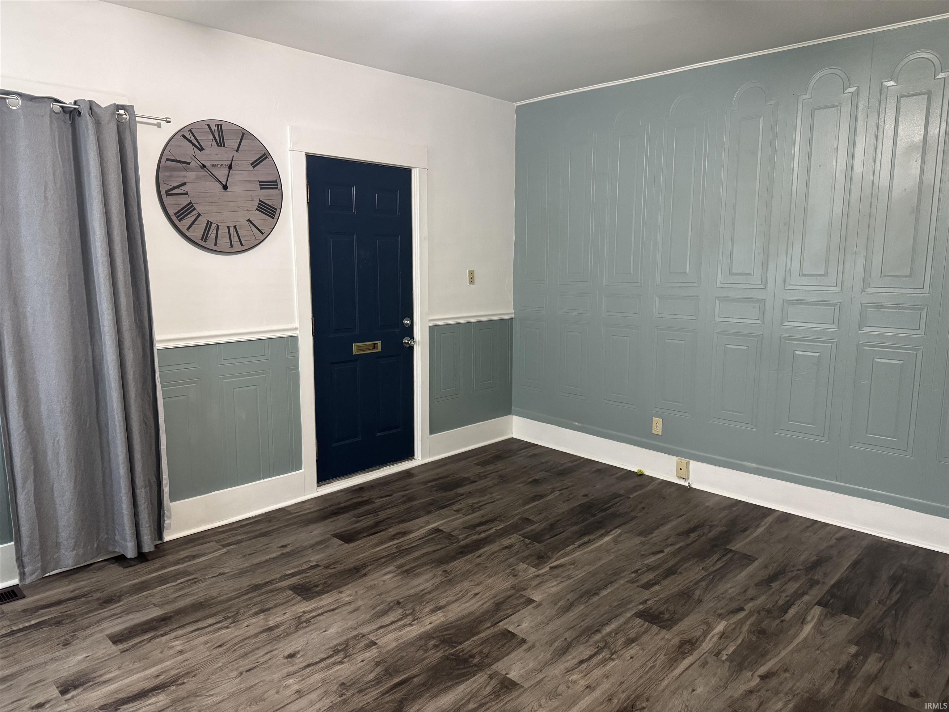 Unit 1 living room featuring, dark wood finished floors, wainscoting, and a decorative wall