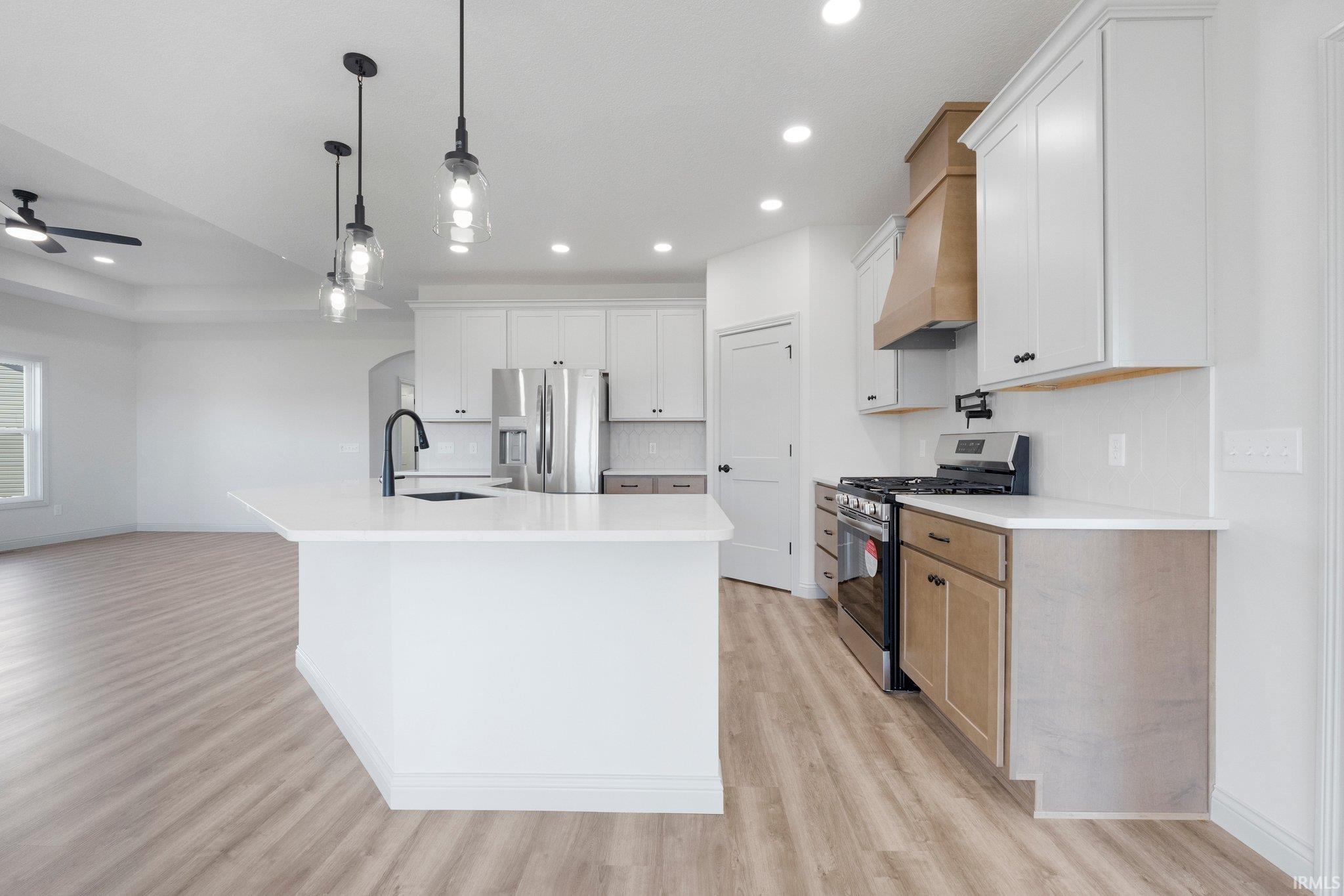 Bright kitchen featuring a central island with a built-in sink and a matte black faucet