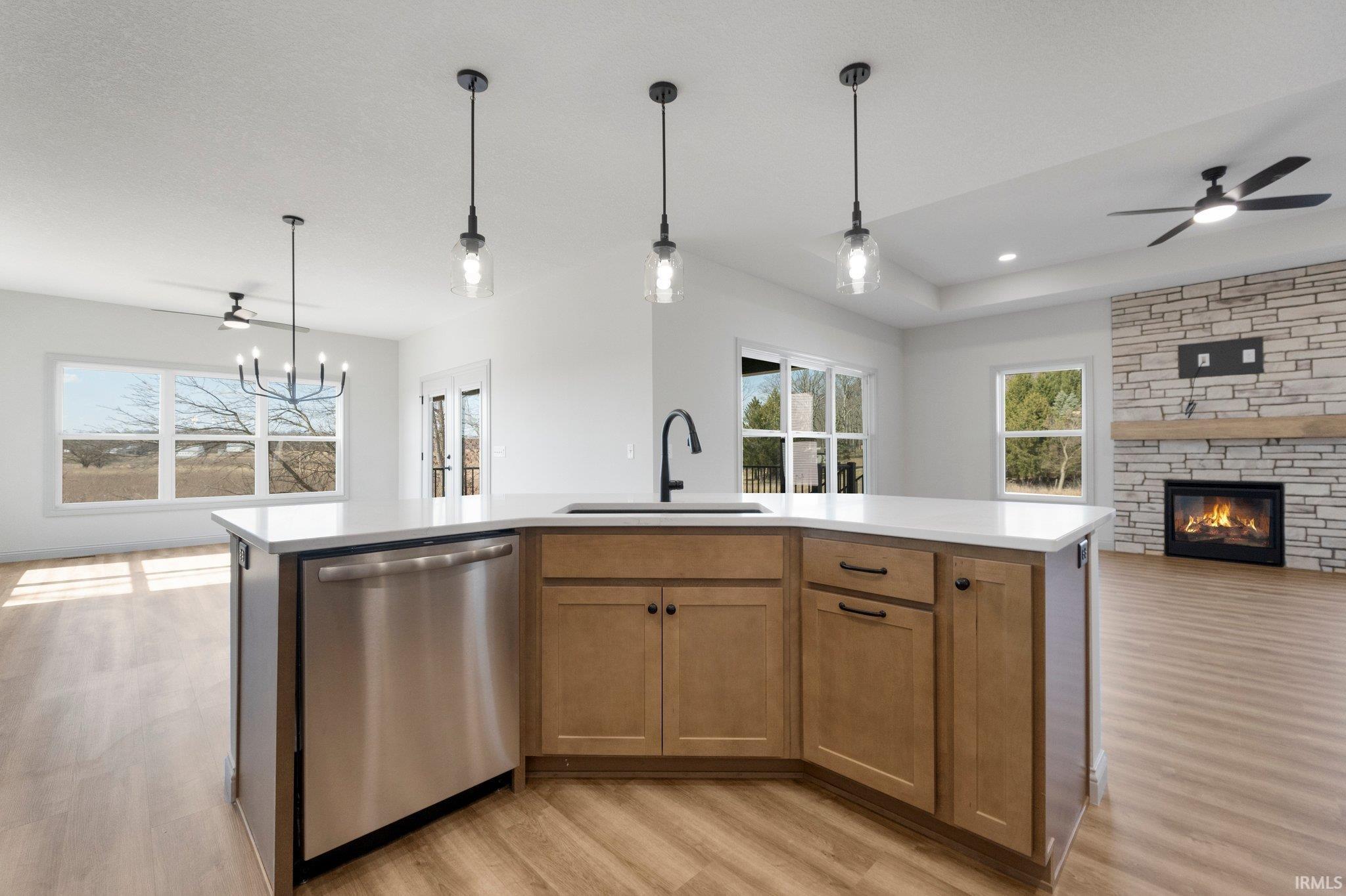 Kitchen island featuring a stainless steel dishwasher, undermount sink, and light wood cabinetry
