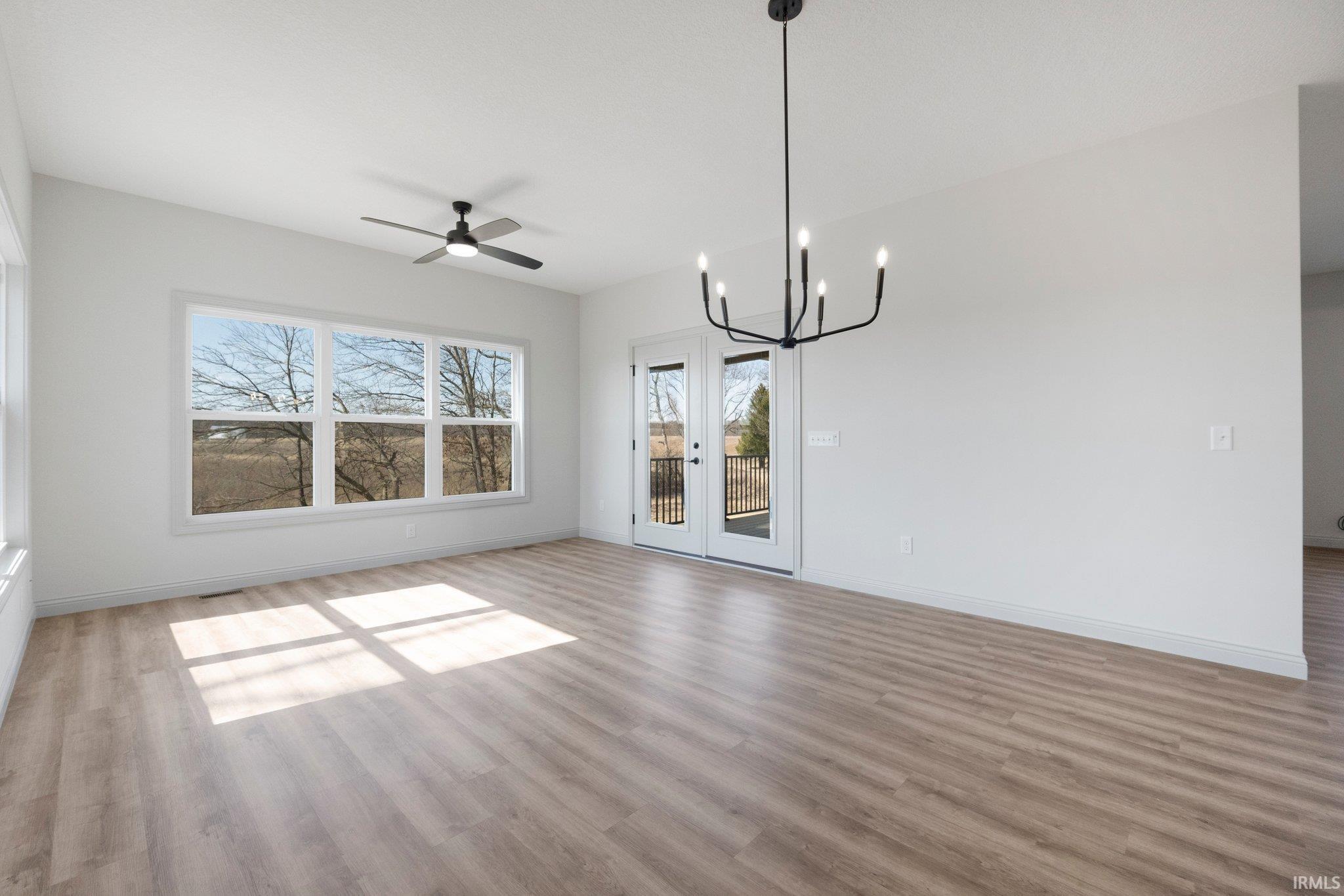 Spacious room with large windows, wood-finish flooring, and a modern black chandelier
