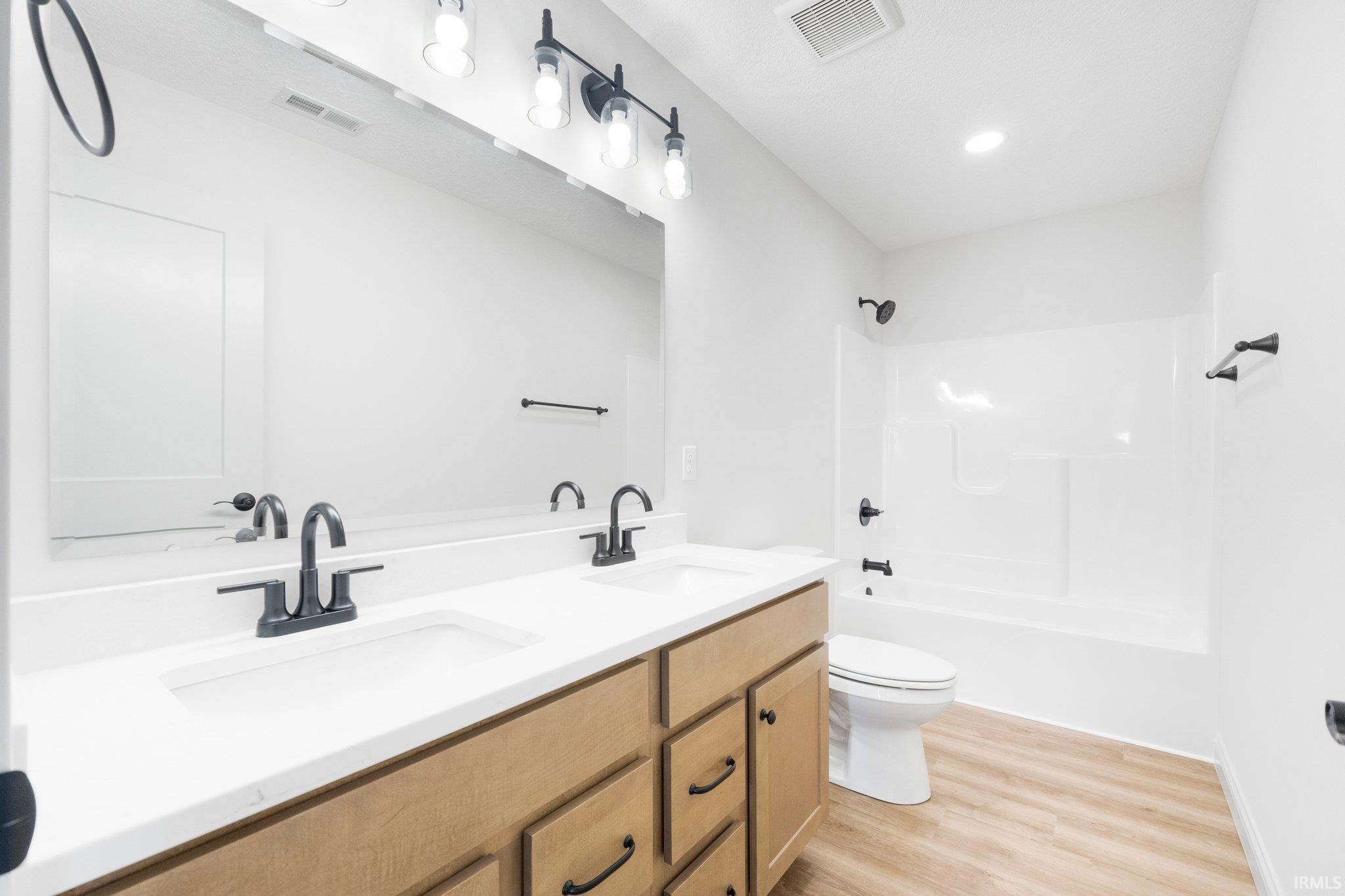 Double vanity with white countertops, light-toned cabinetry, and black hardware