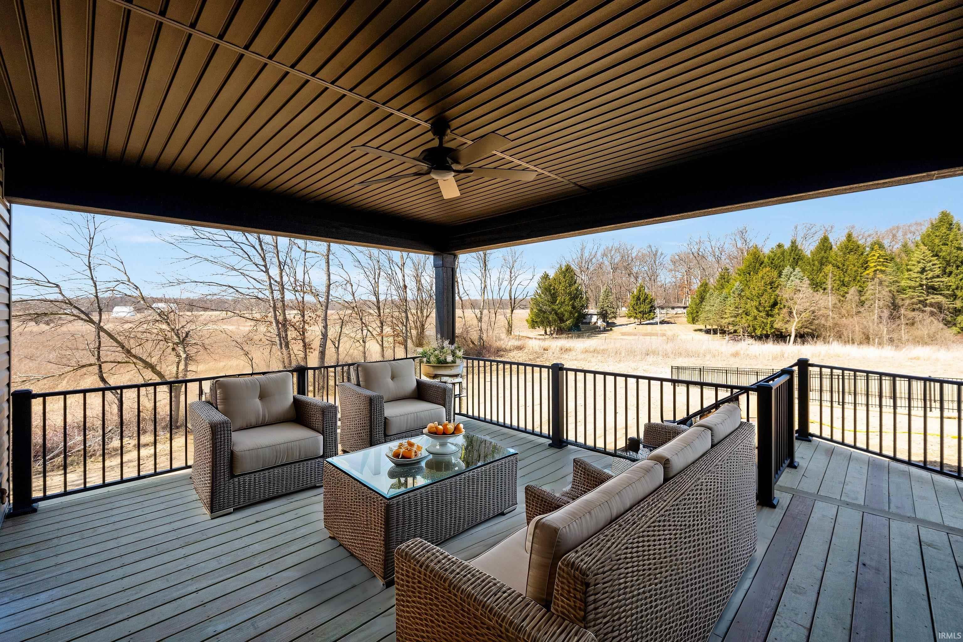 Expansive covered deck featuring composite decking, black metal railing, and a ceiling fan