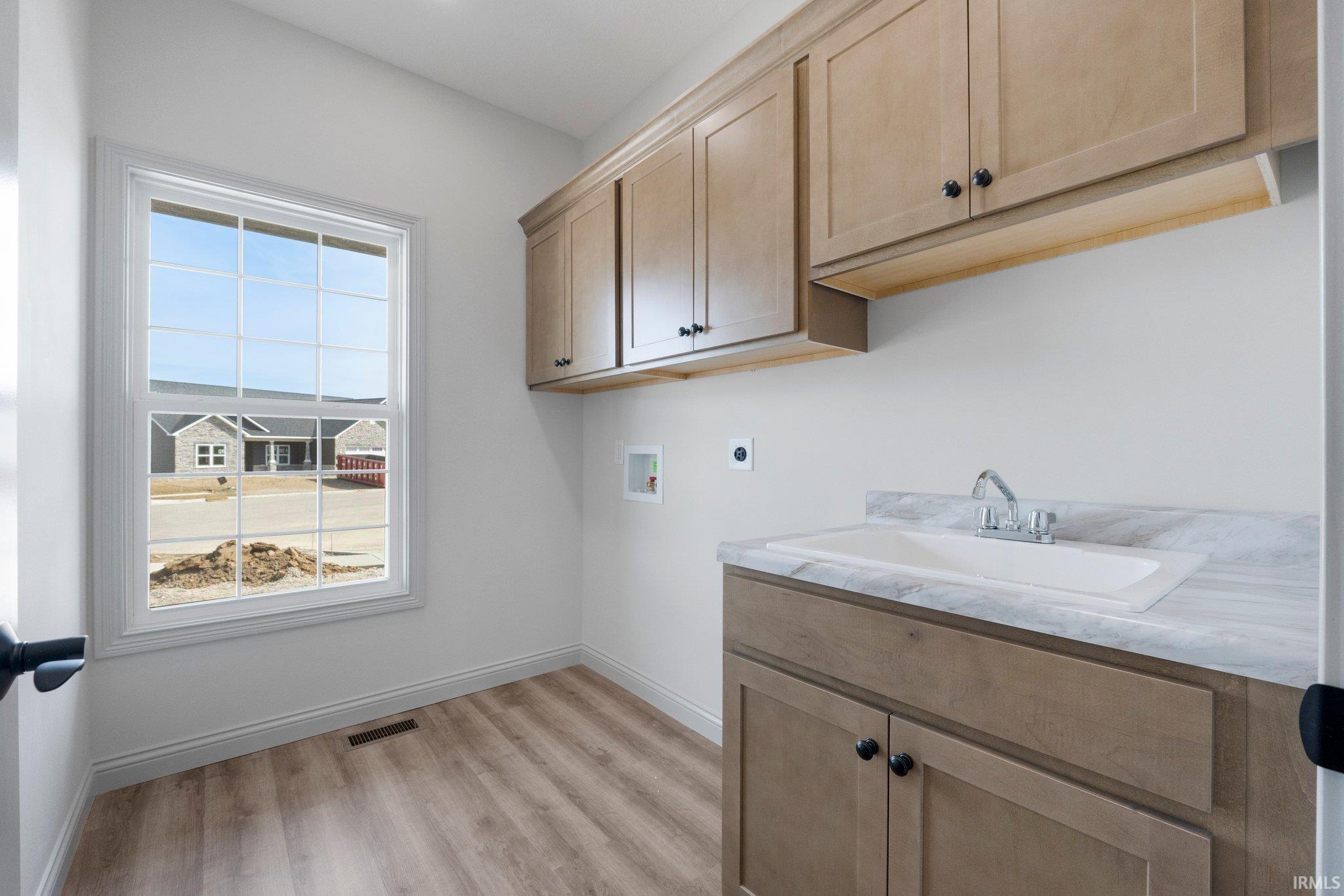 Utility room featuring wood-finish flooring and a double-hung window